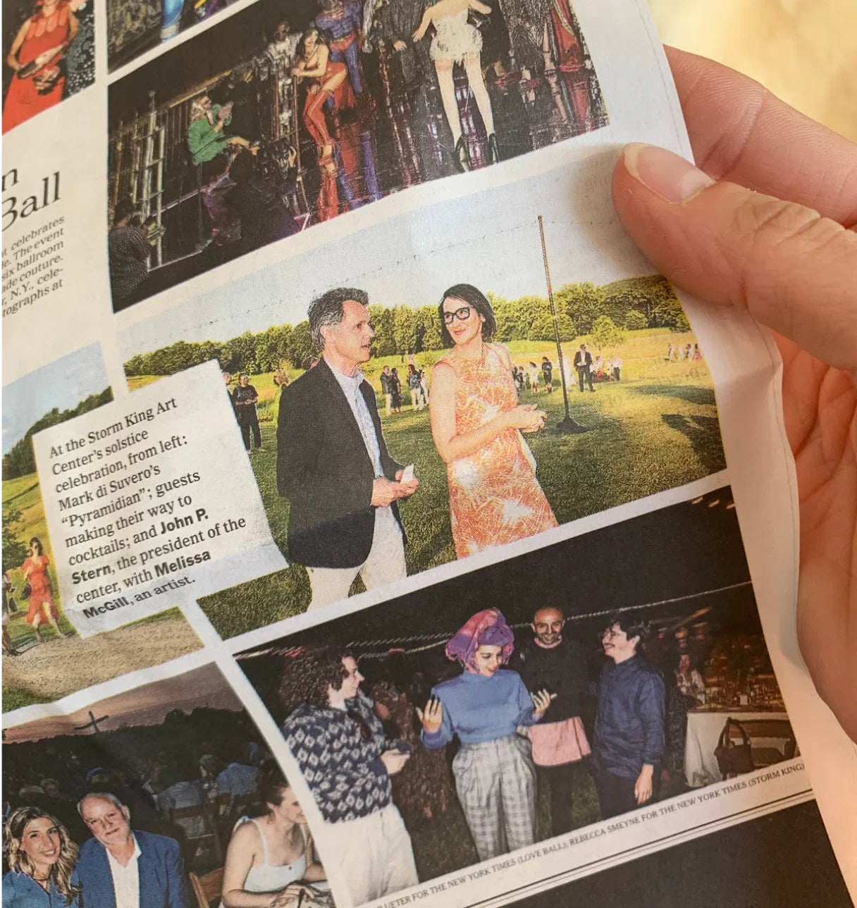Woman in a modern mu'umu'u dress at an outdoor event, holding a newspaper page