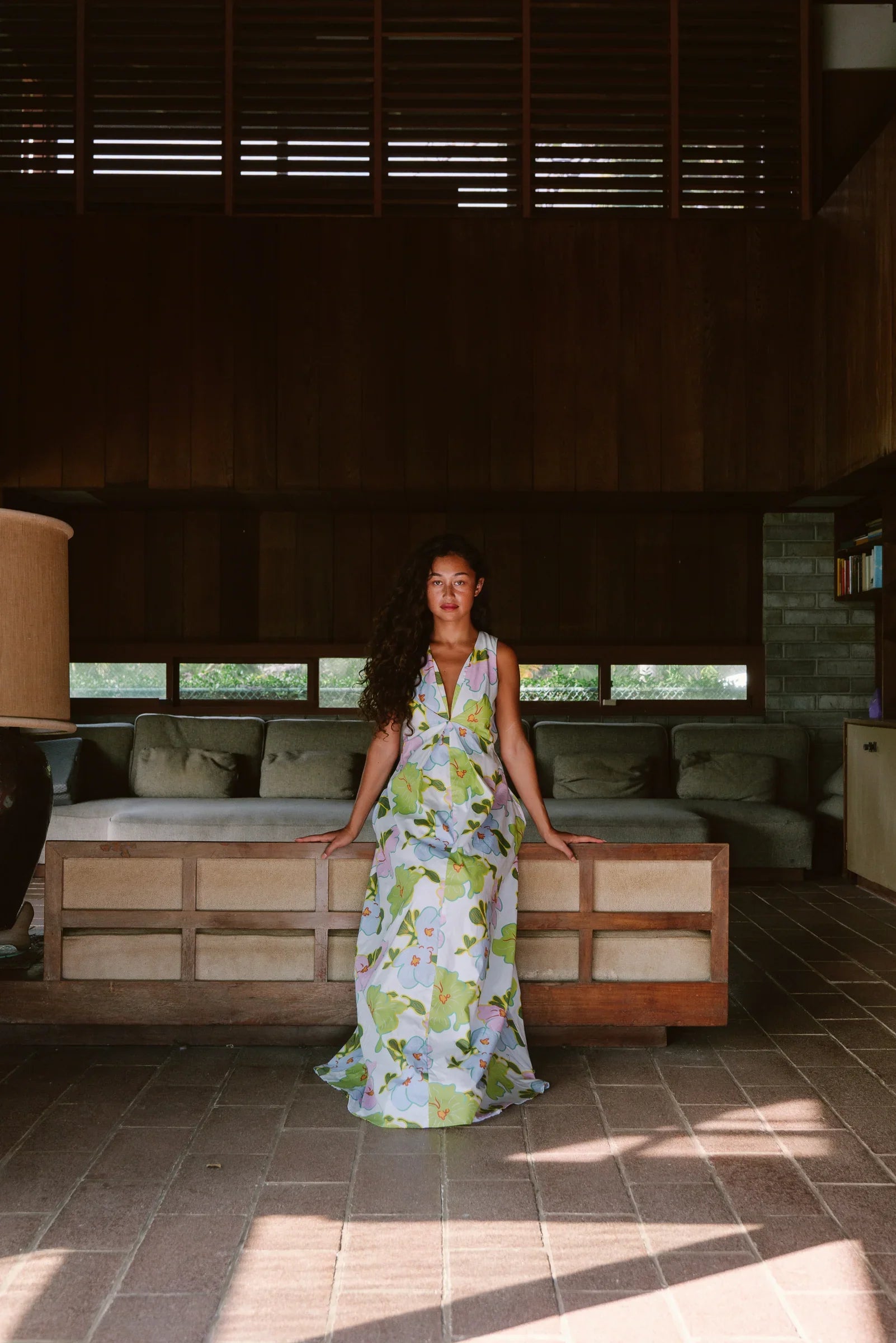Woman in a modern floral mu'umu'u dress sitting in a stylish, mid-century room