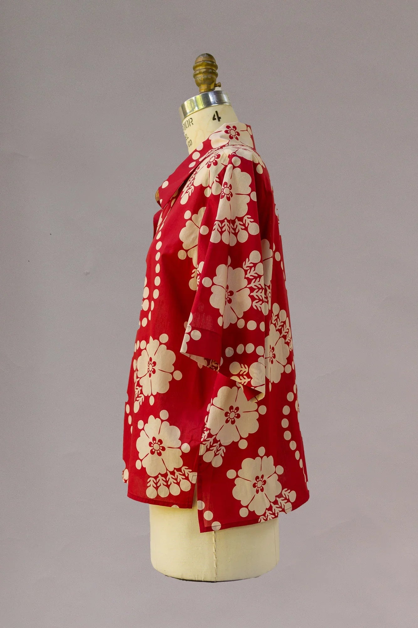Red Hawaiian shirt with cream floral print on mannequin, short sleeves, tropical style