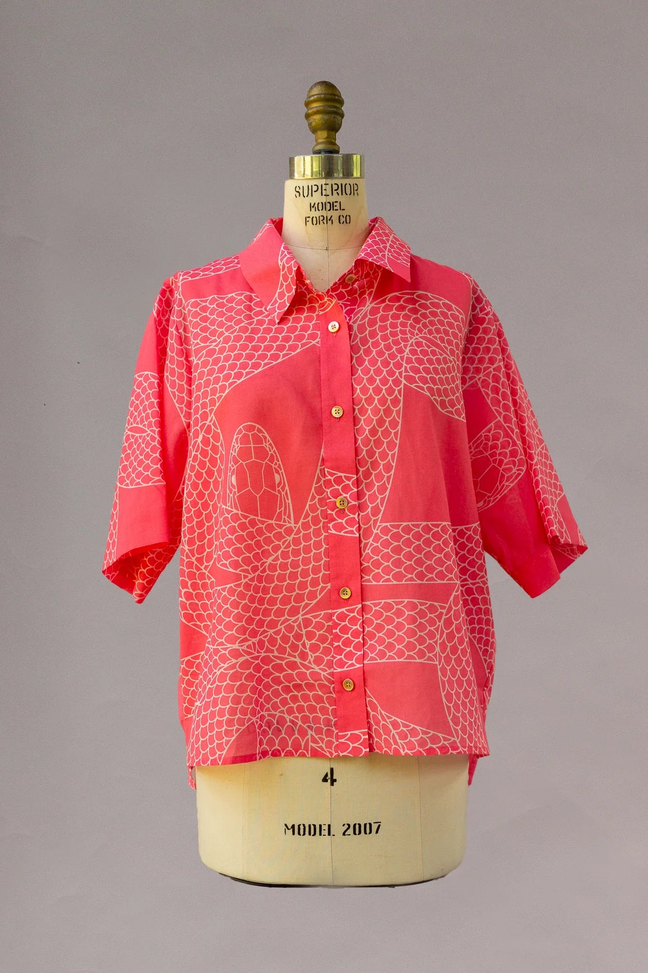 Red Hawaiian shirt with abstract snake print and short sleeves on dress form