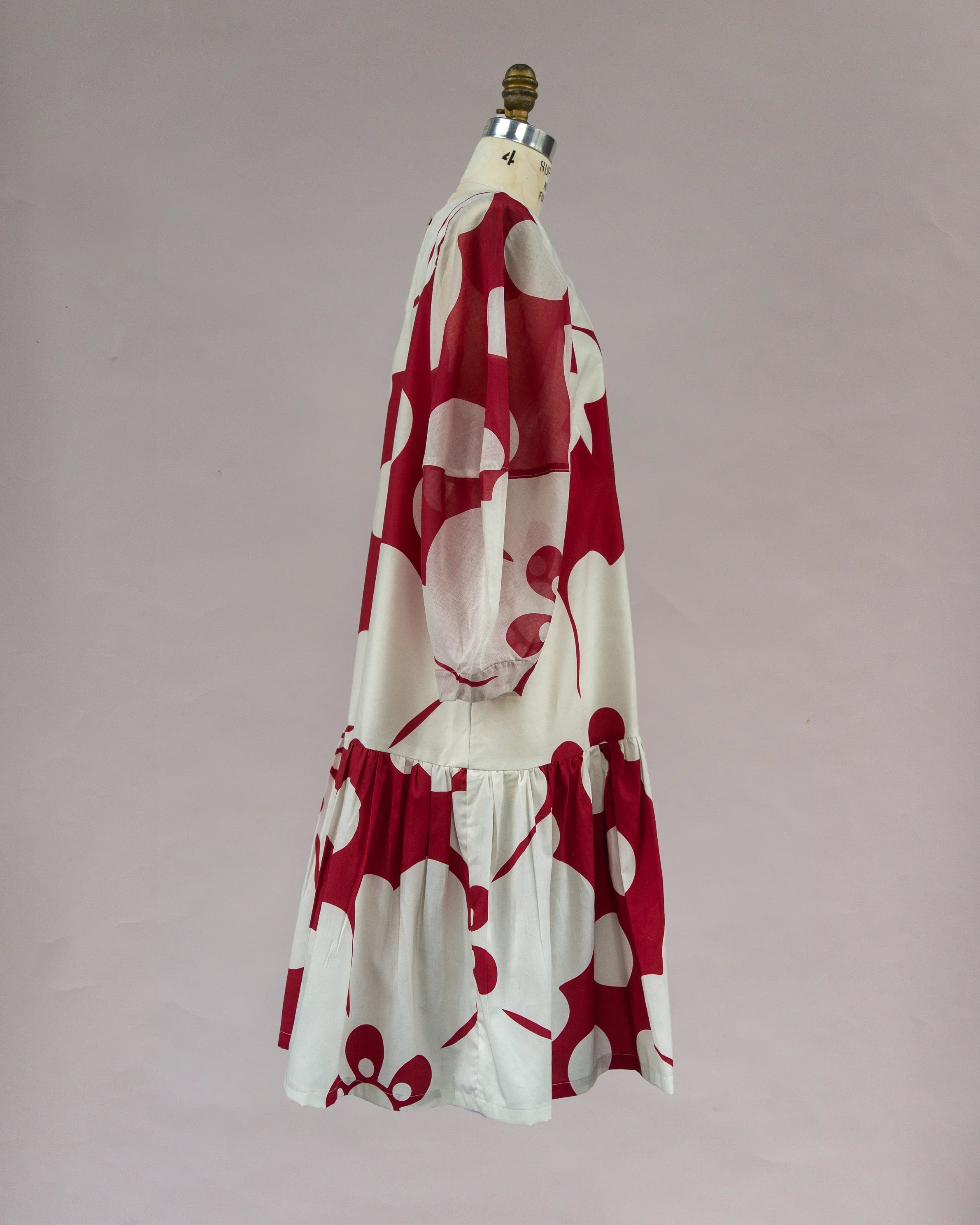 Red and white floral mu'umu'u dress with long sleeves and ruffled hem on mannequin