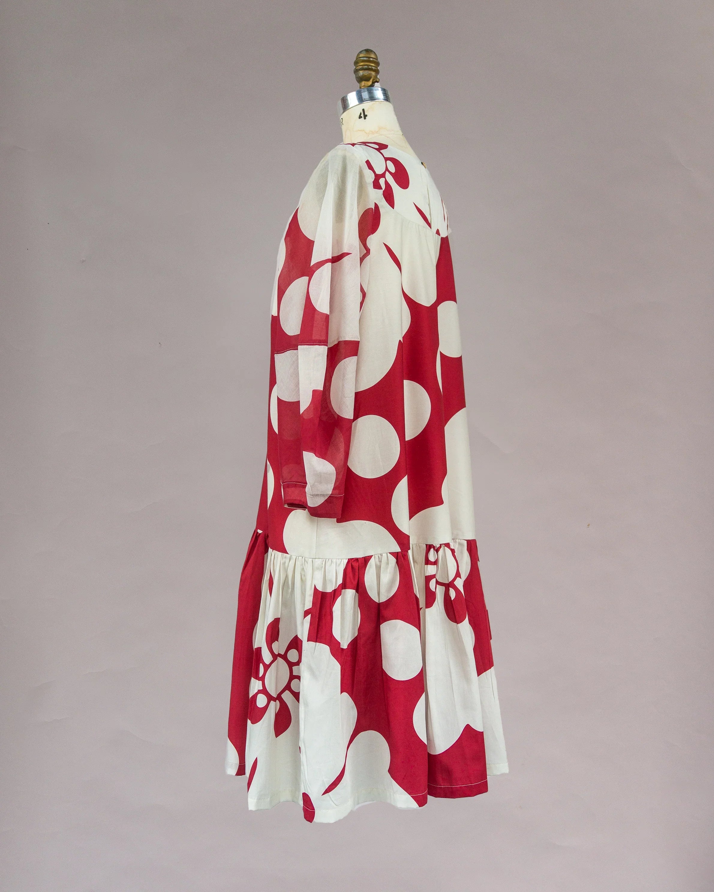 Red and white Hawaiian print muumuu dress with long sleeves on mannequin