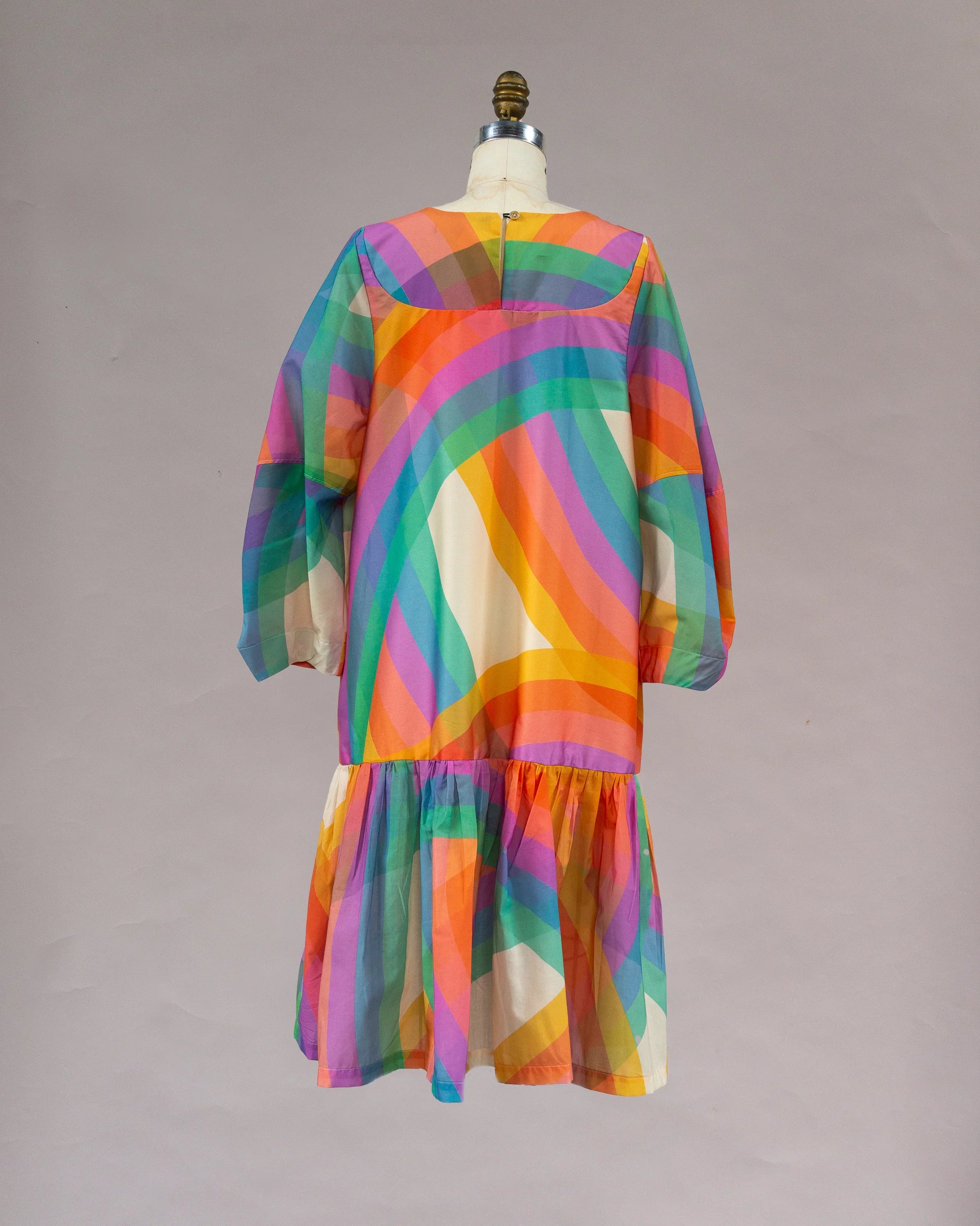 Long sleeve muumuu dress with bold rainbow striped Hawaiian print on mannequin