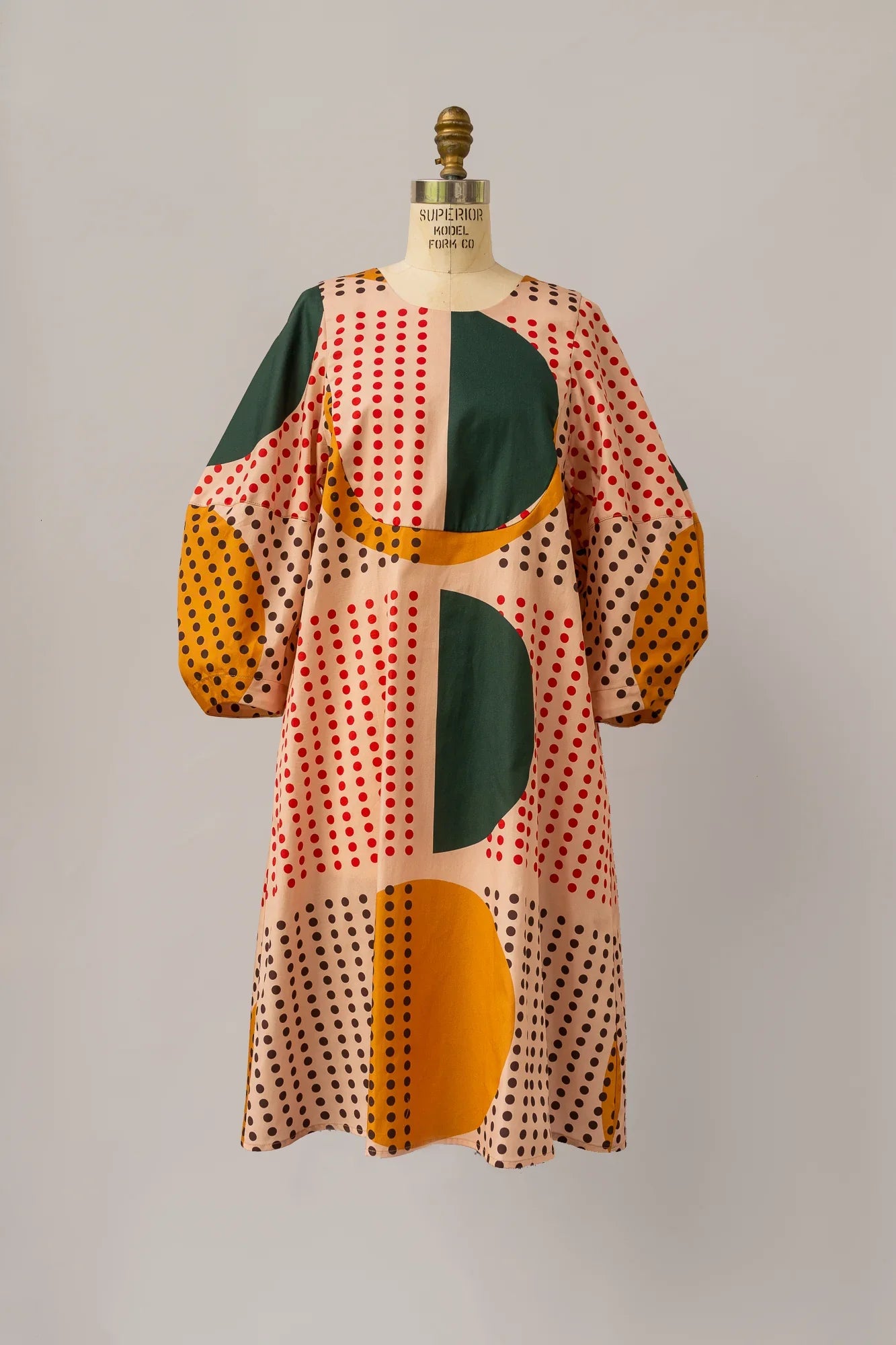 Modern mu'umu'u dress with bold geometric and polka dot pattern in green, yellow, and red