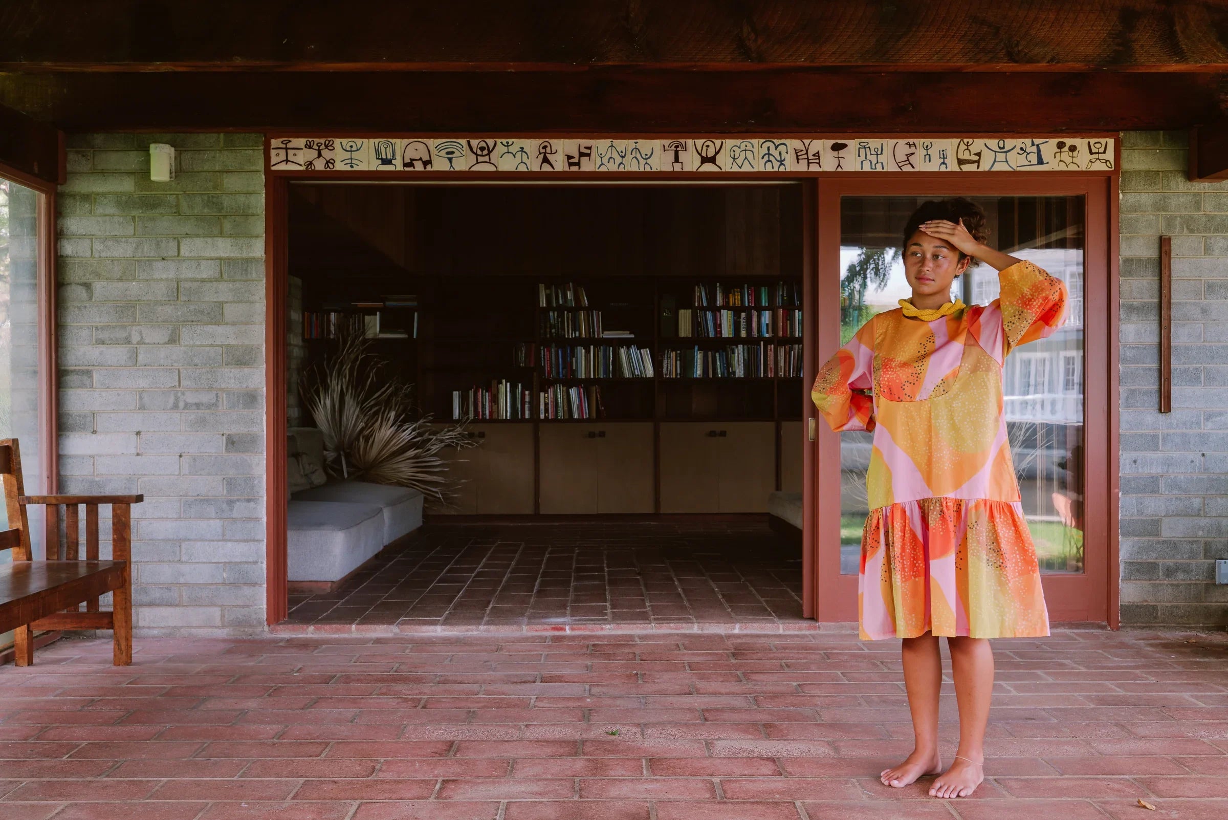 Woman in a colorful modern muumuu dress with Hawaiian print standing on a brick patio