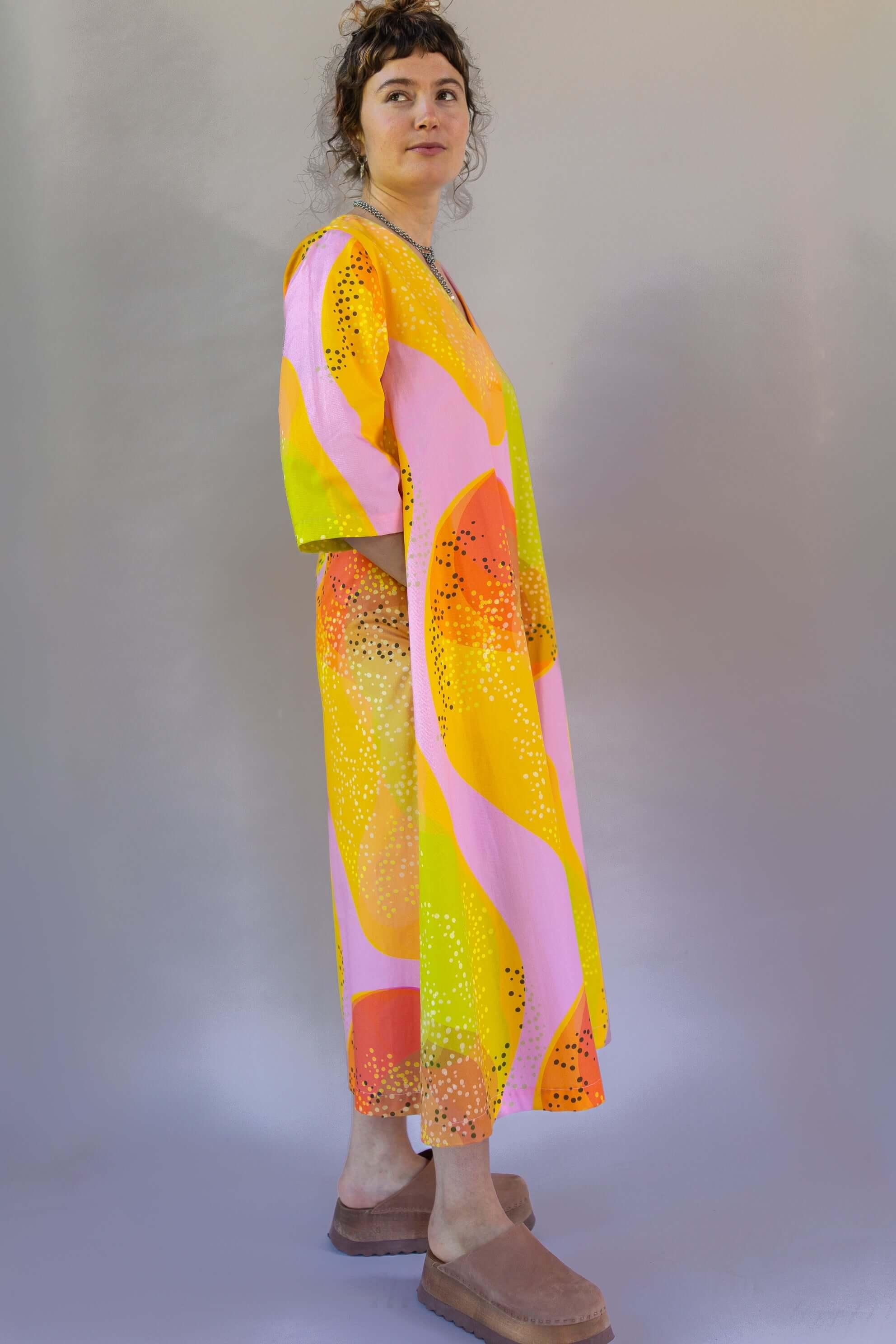 Woman in a modern mu'umu'u dress with pink, yellow, and orange Hawaiian print