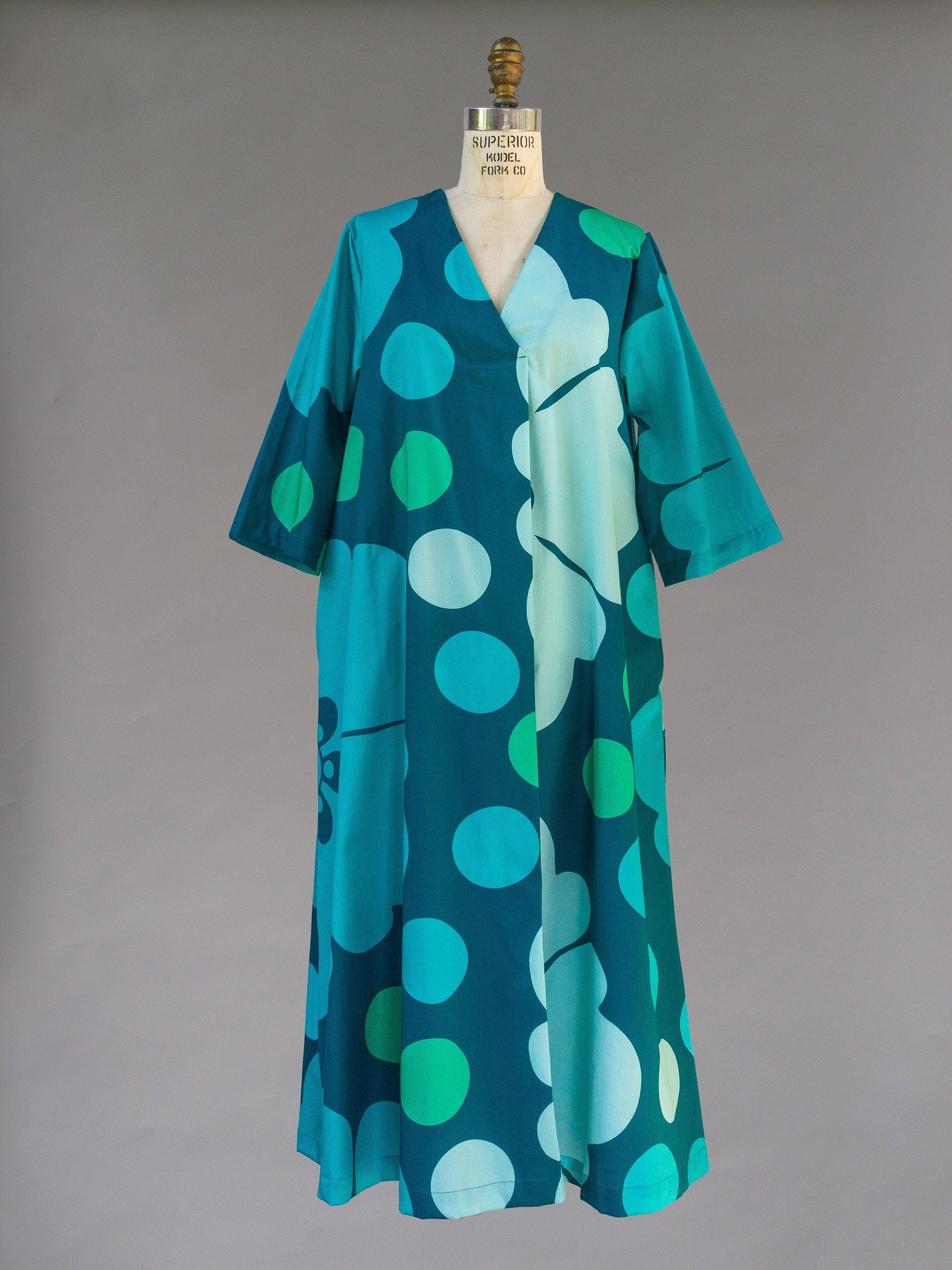 Teal and blue muumuu dress with bold polka dot Hawaiian print on mannequin