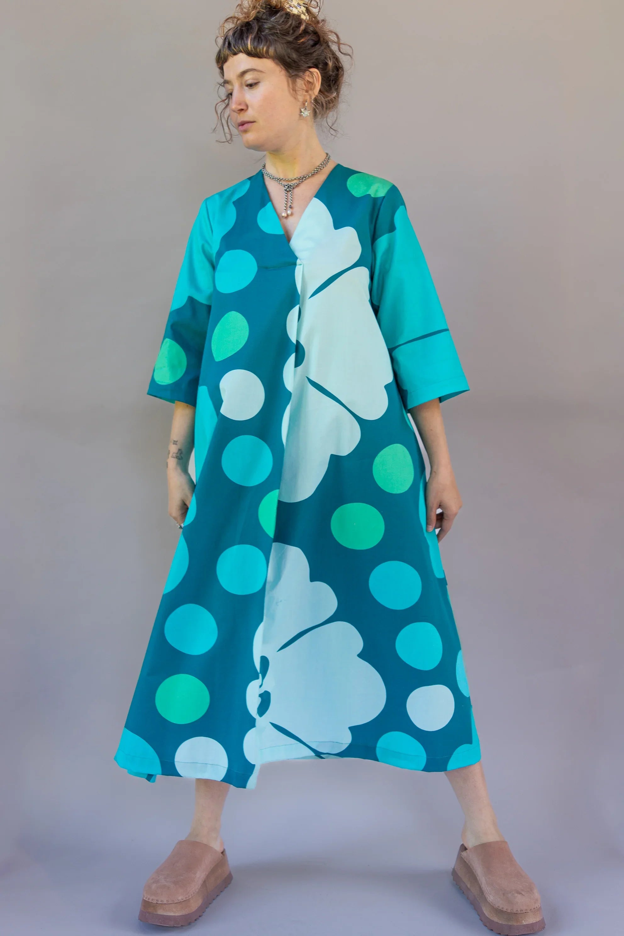 Woman wearing a teal muumuu dress with bold polka dots and Hawaiian floral print