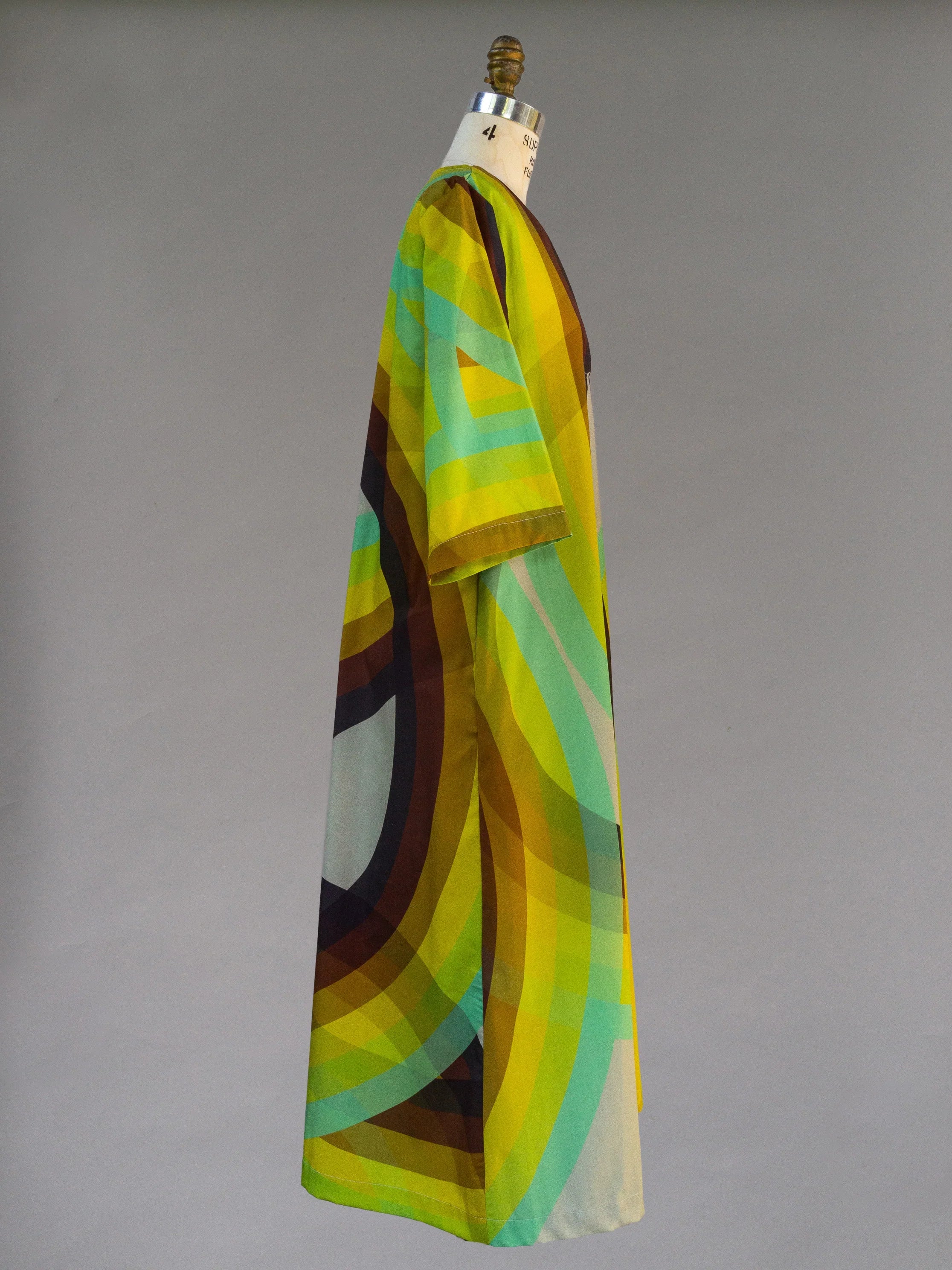 Side view of a modern mu'umu'u dress with rainbow geometric Hawaiian print on mannequin