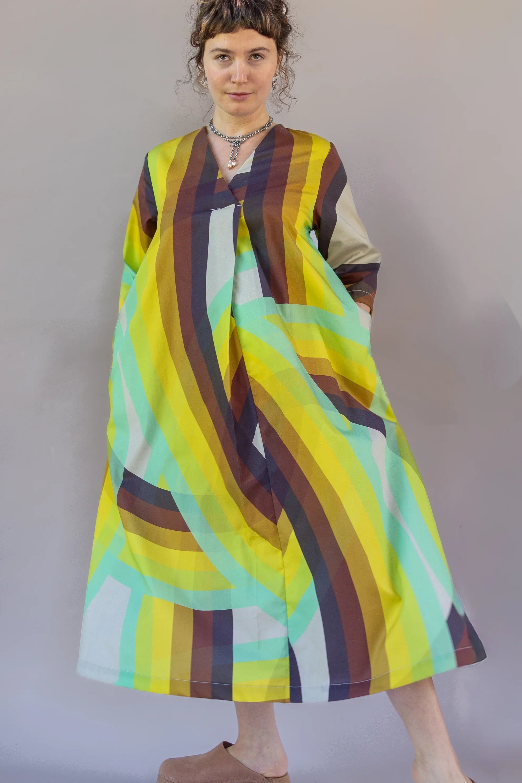 Woman wearing a modern mu'umu'u dress with bold, colorful rainbow stripes