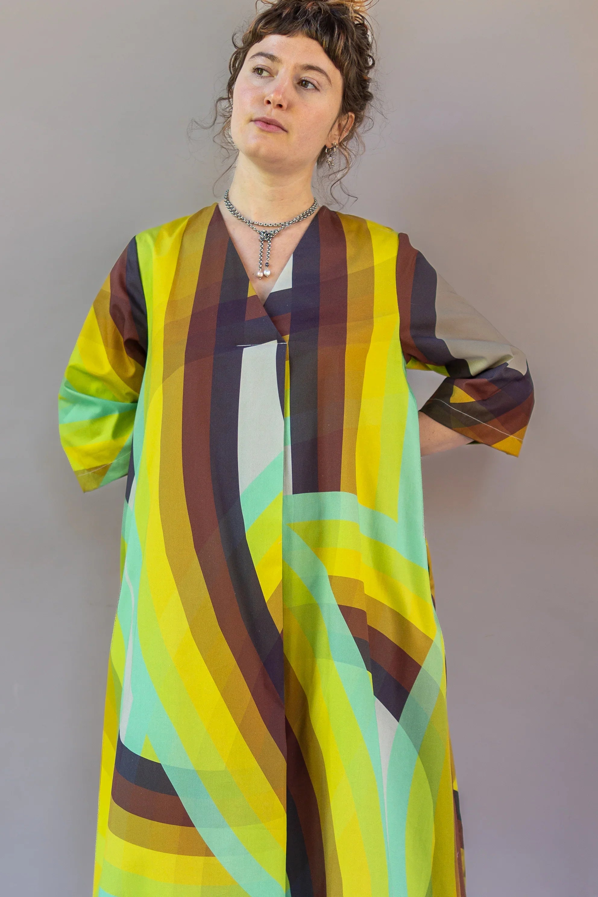 Woman wearing modern mu'umu'u dress with bold yellow, green, and brown abstract print