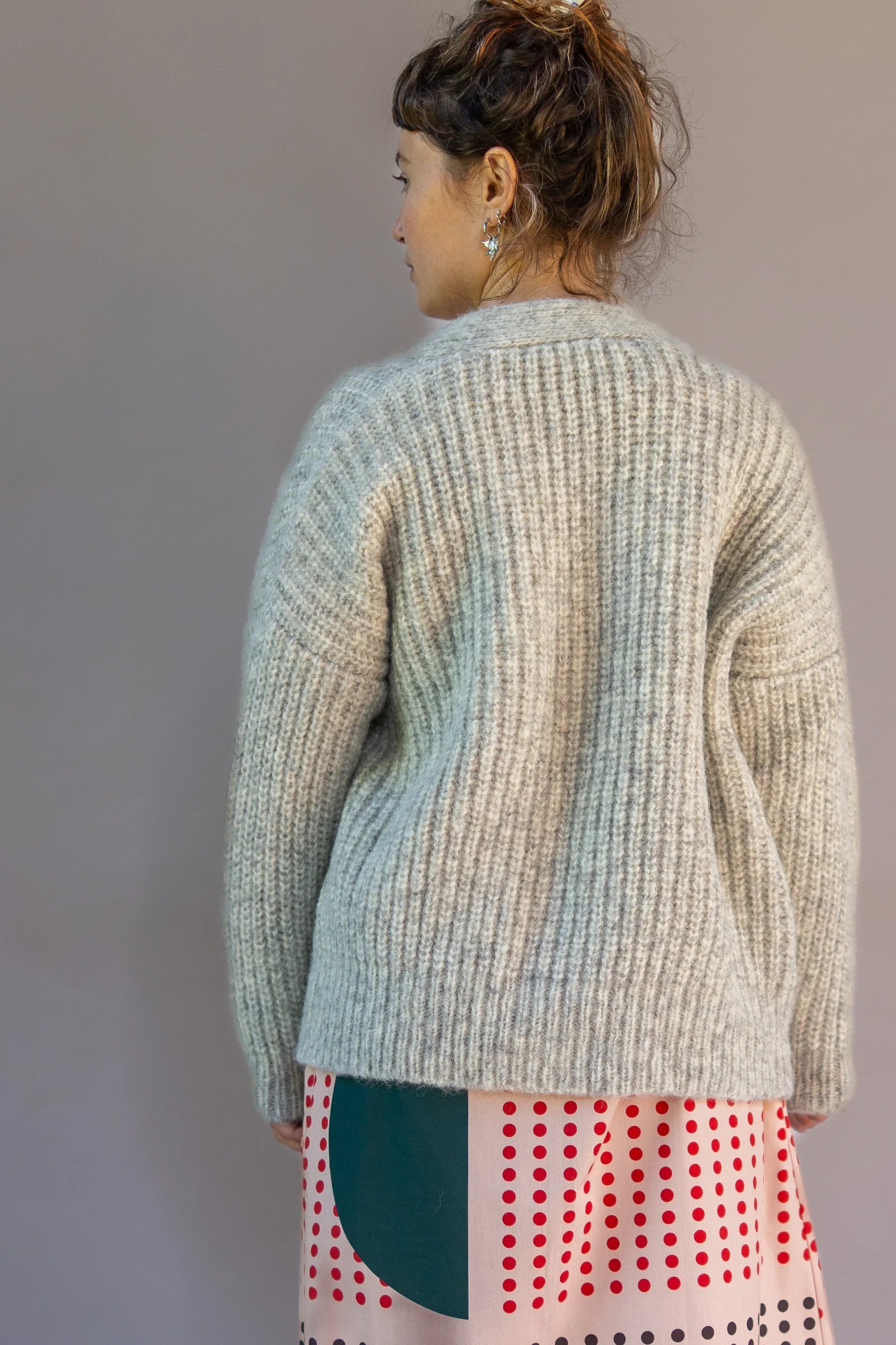 Woman in gray ribbed sweater and modern Hawaiian print dress, photographed from behind