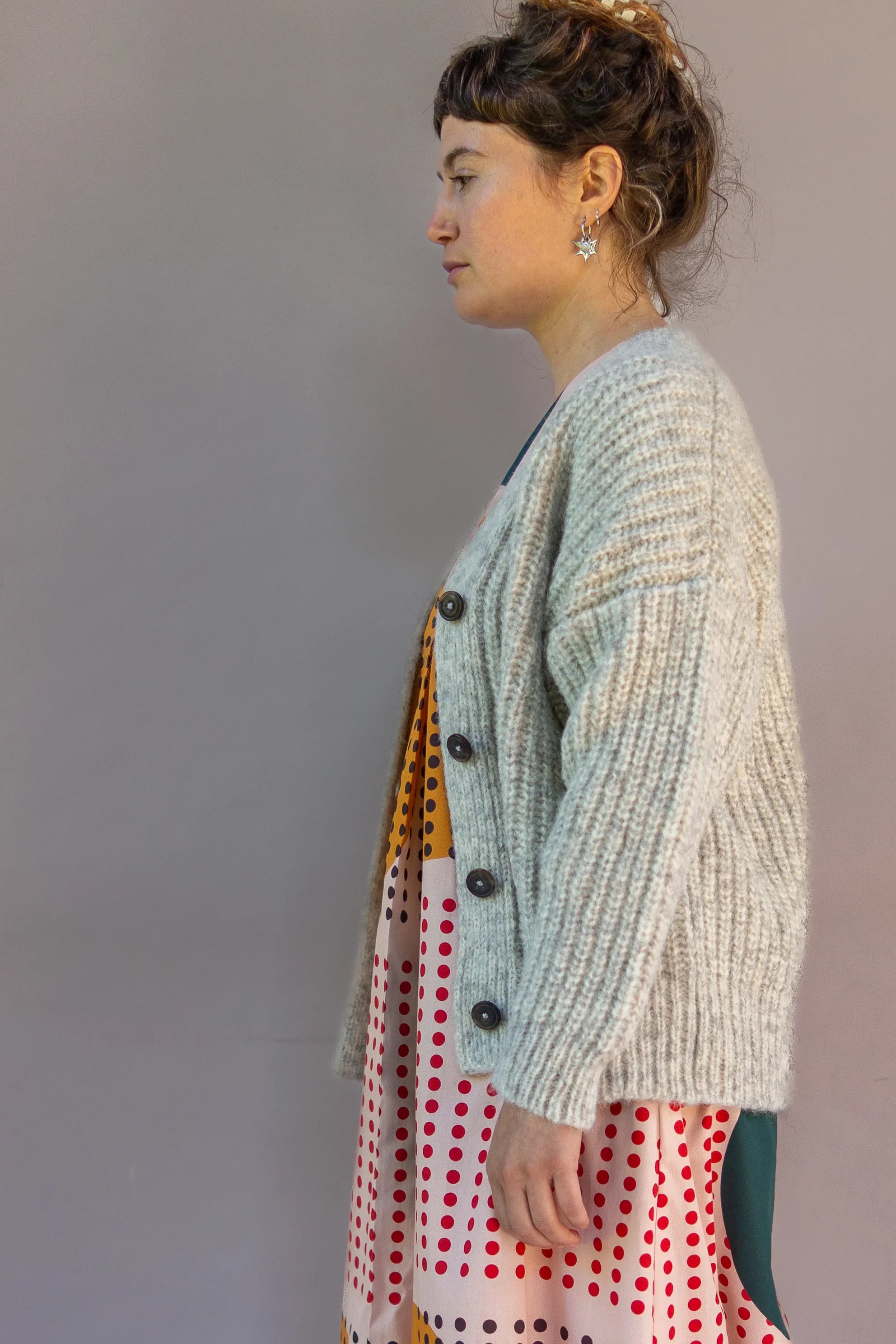 Woman in modern mu'umu'u dress with colorful polka dot print and chunky knit cardigan