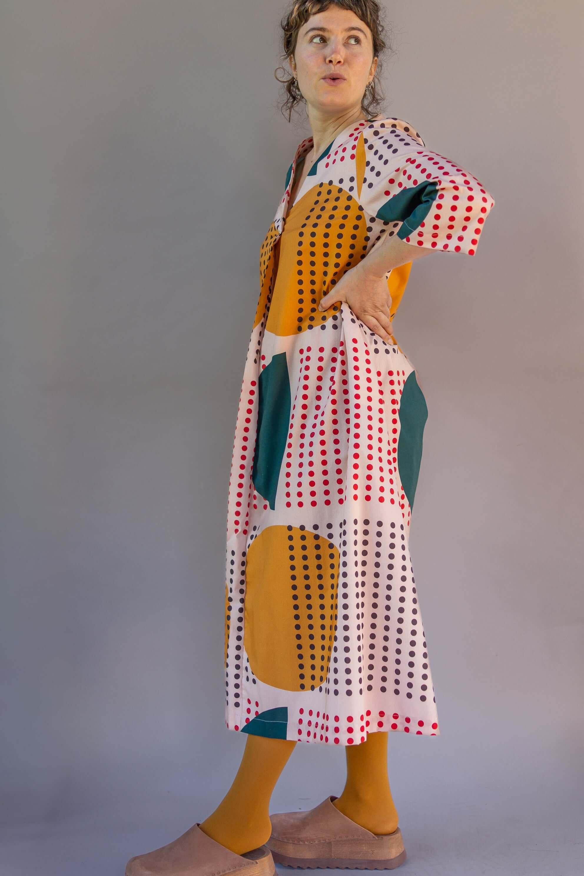 Woman wearing a modern mu'umu'u dress with bold, colorful dot and geometric prints