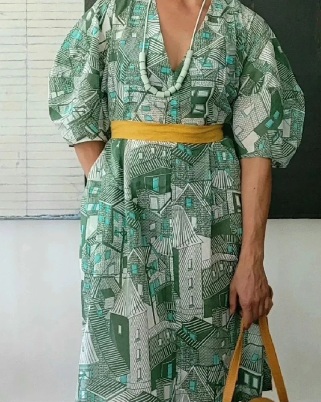 Woman in modern mu'umu'u dress with green architectural print and yellow belt
