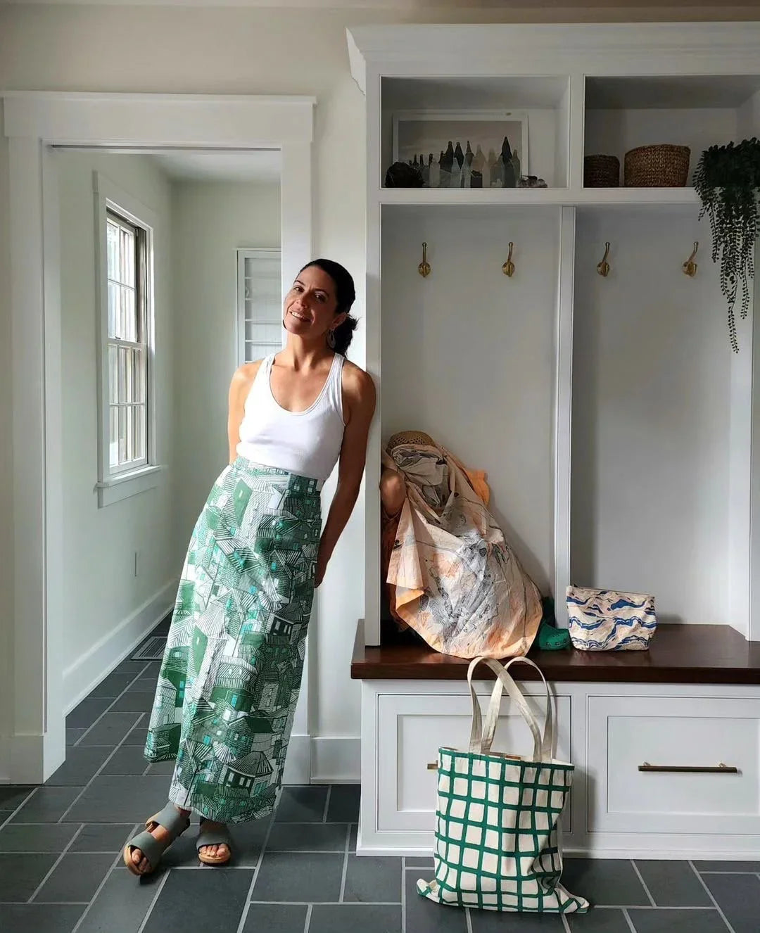 Woman in a white tank top and green Hawaiian print skirt standing in a modern mudroom