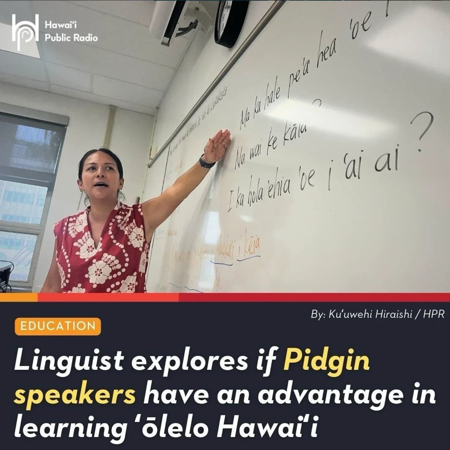 Teacher in floral dress gestures at Hawaiian sentences on classroom whiteboard, educational setting.