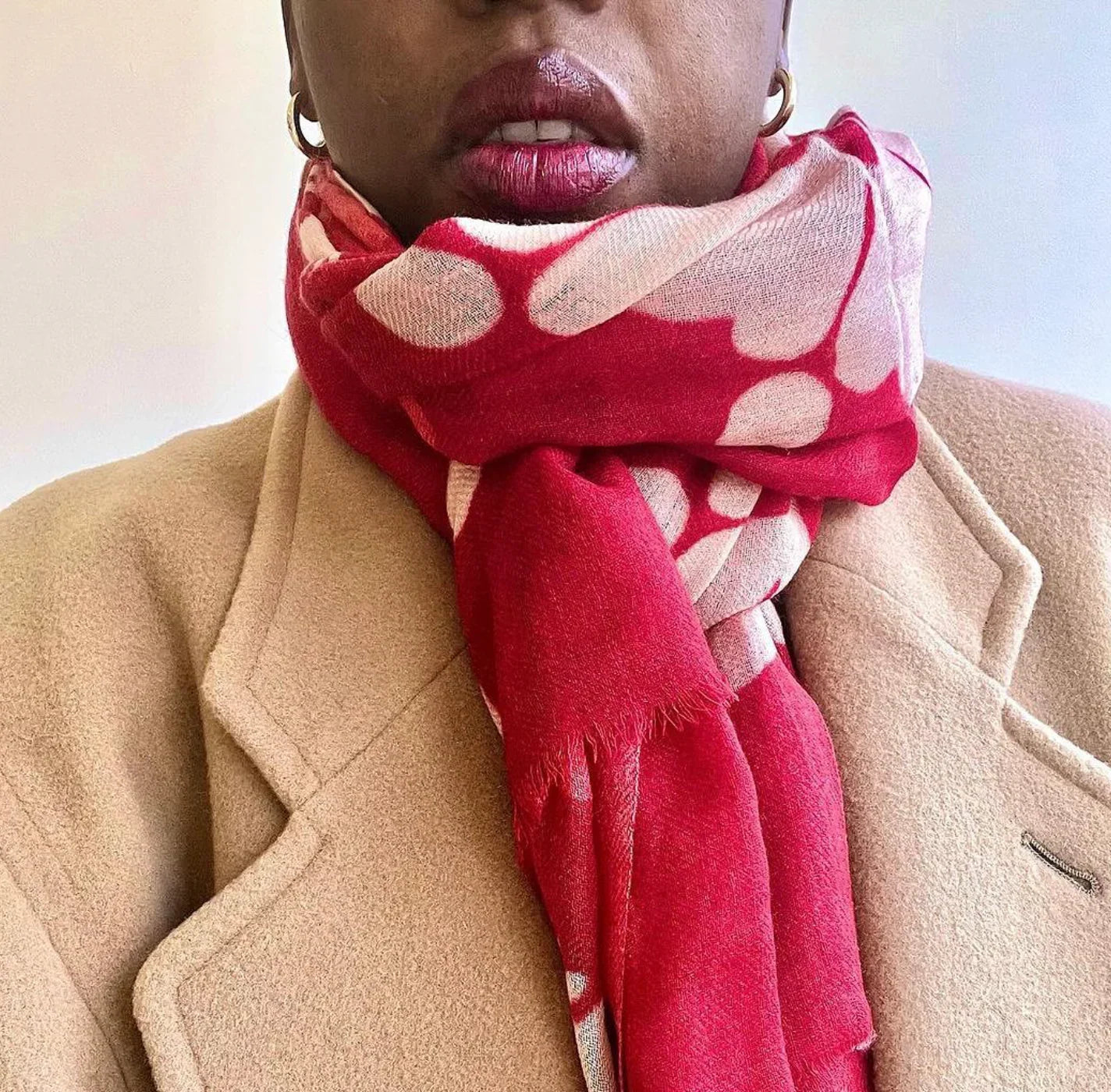 Woman in tan coat wearing pink patterned scarf with bold modern print