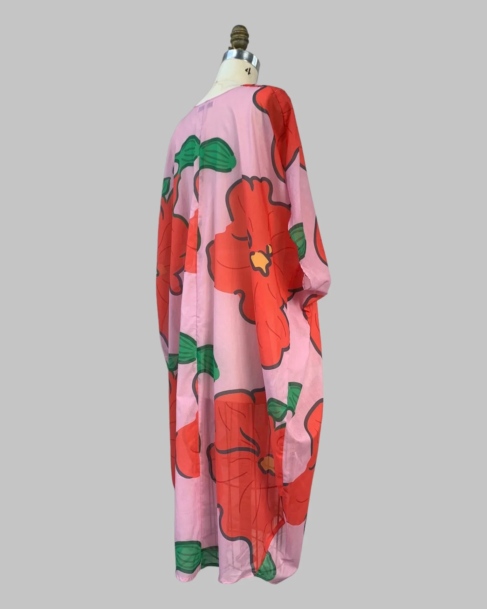 Pink muumuu kaftan with bold red tropical floral print on a mannequin