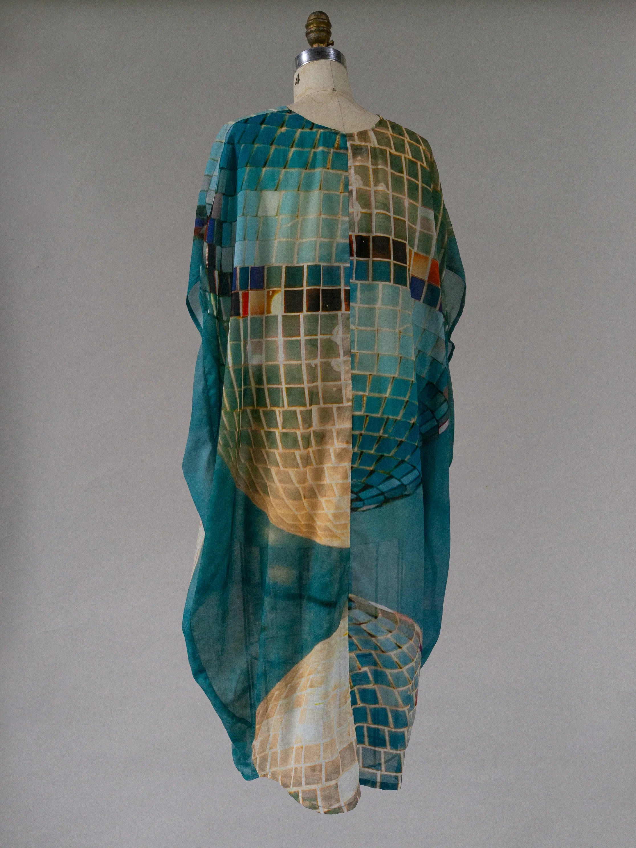 Sheer kaftan dress with abstract grid print in blue, teal, and yellow tones on mannequin