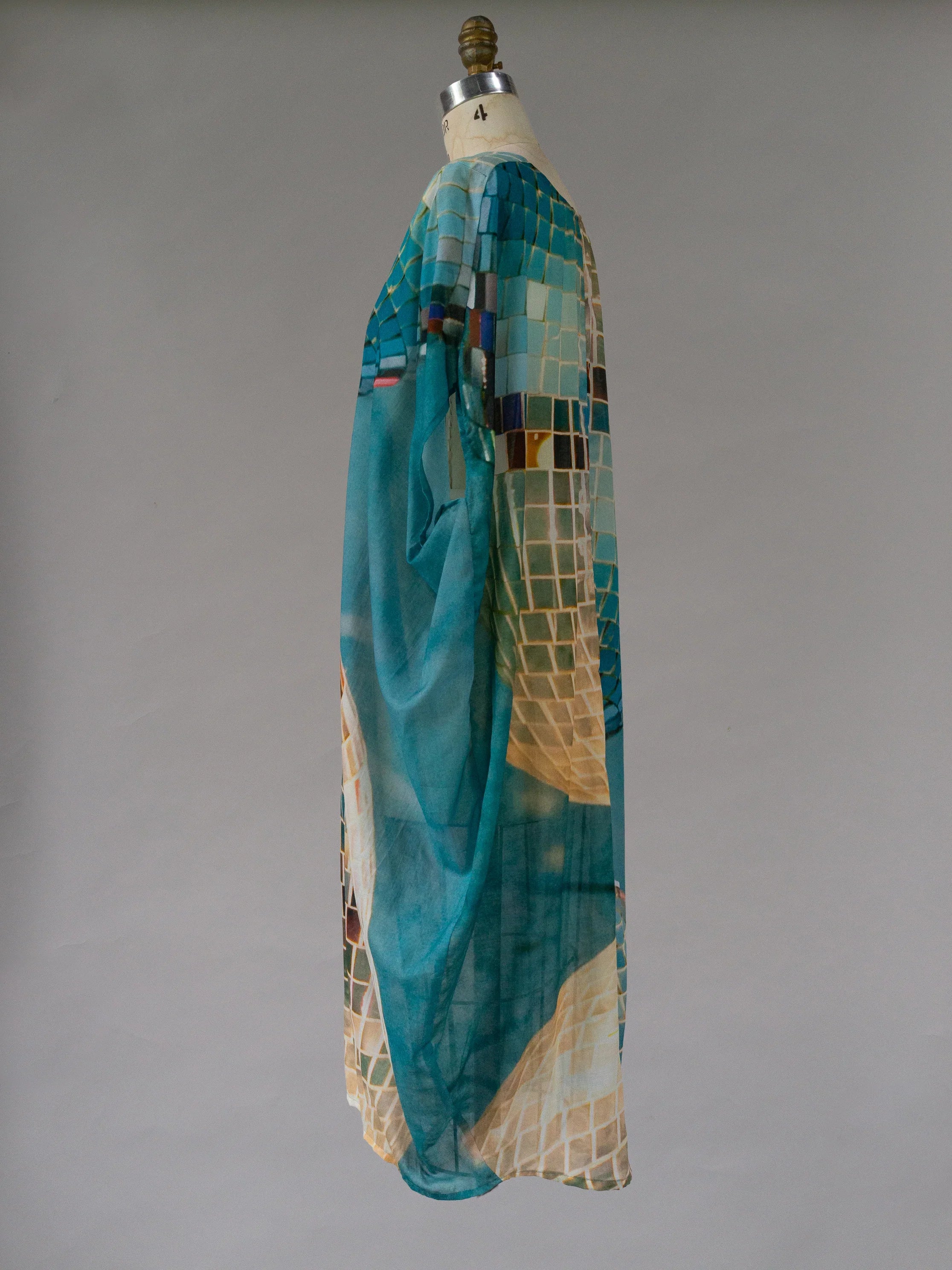 Sheer teal kaftan with geometric mosaic print, displayed on mannequin, side view