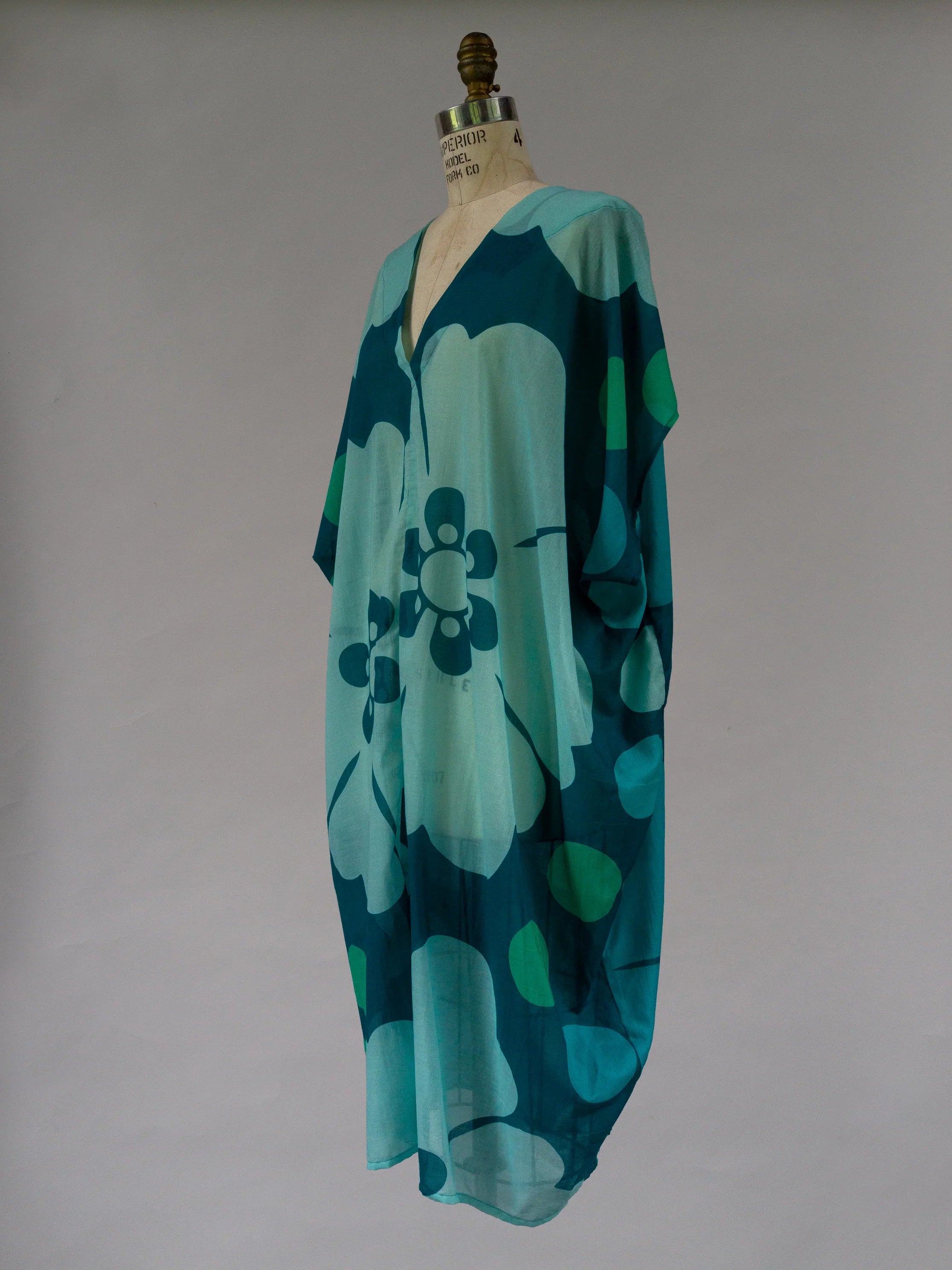 Flowy ocean blue kaftan with oversized floral print on dress form