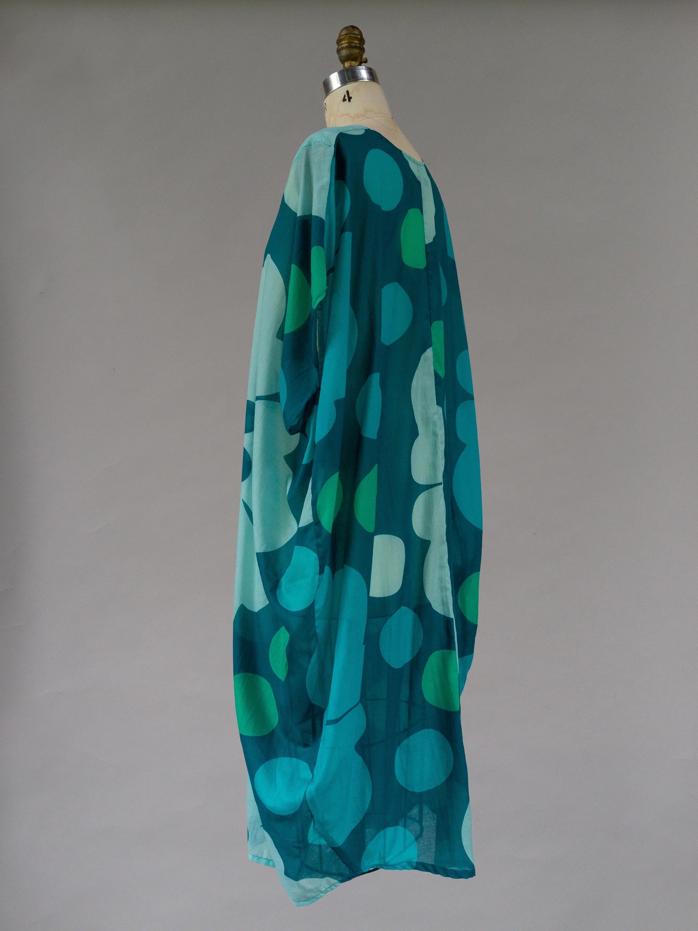 Flowy oversized kaftan with teal and green abstract dot pattern on dress form