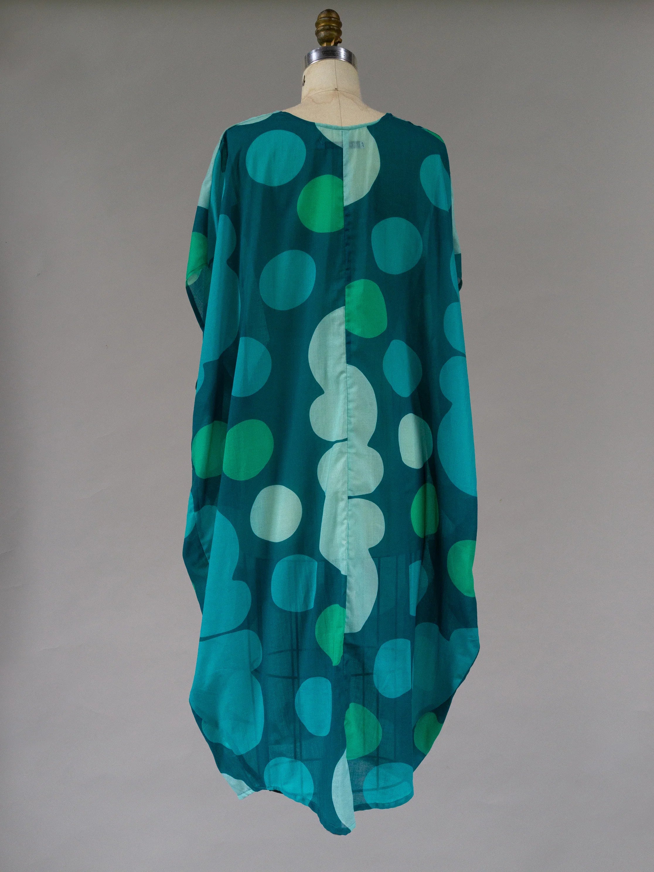 Teal kaftan dress with large green polka dot pattern, displayed on mannequin