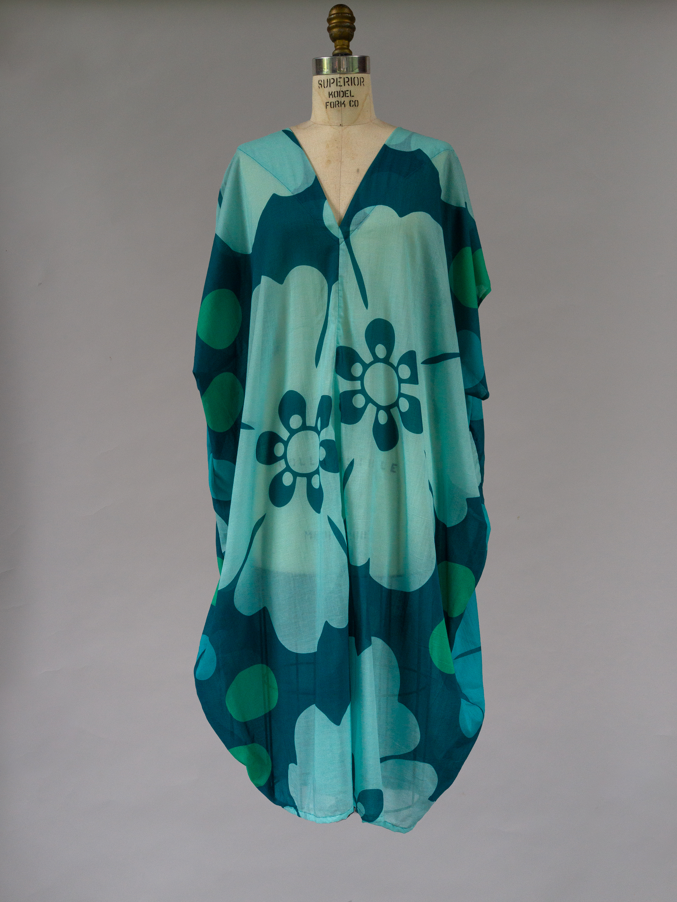 Teal and green floral patterned dress on a mannequin against a plain background