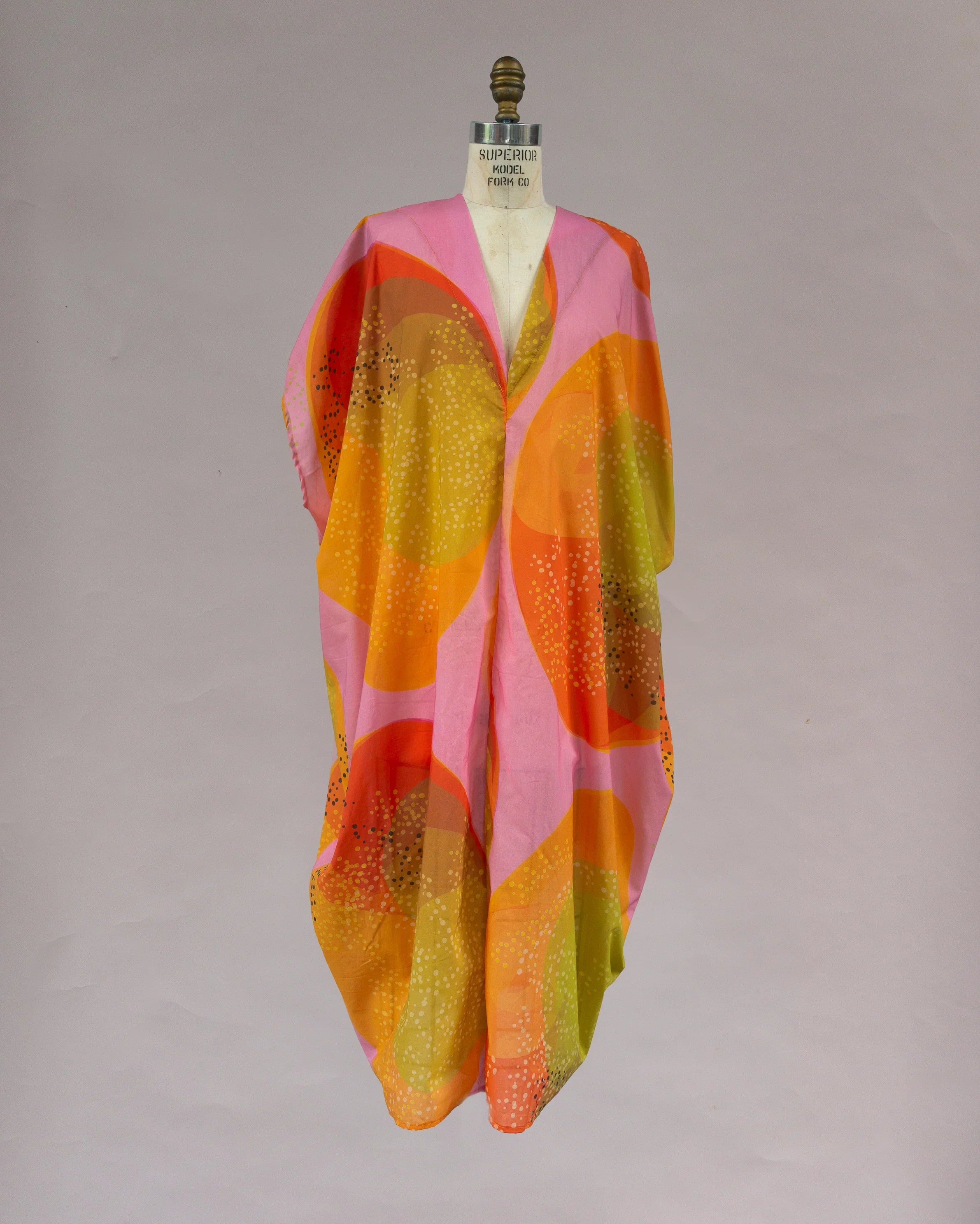 Bright pink, orange, and yellow kaftan with abstract Hawaiian print on mannequin