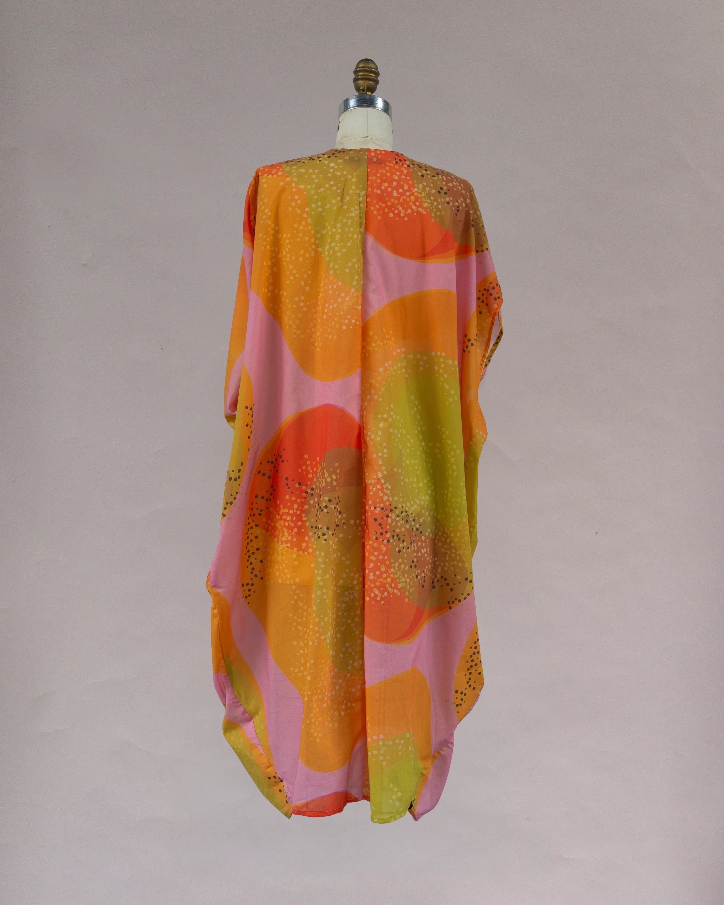 Back view of a colorful kaftan with abstract orange, pink, and yellow Hawaiian print