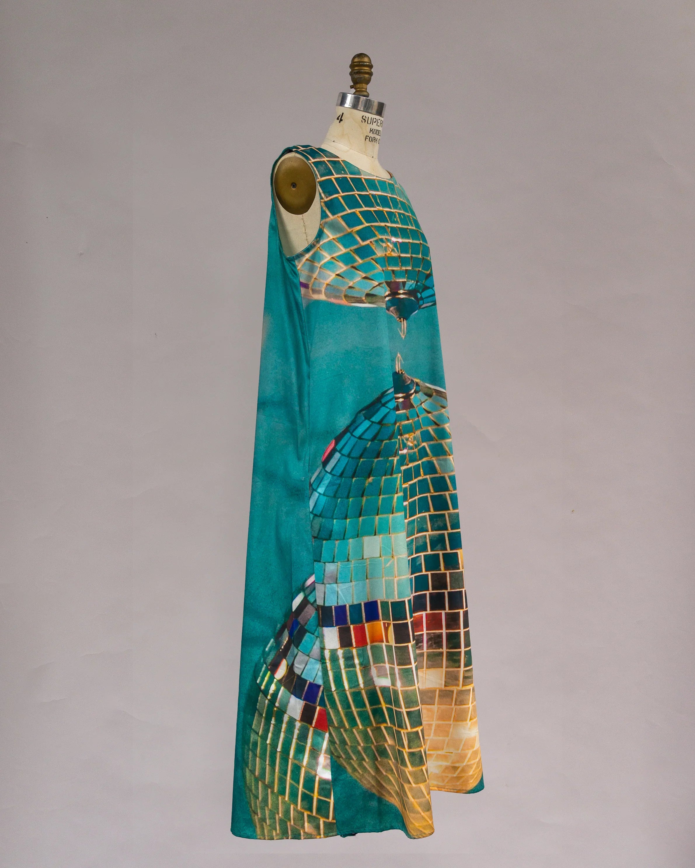 Sleeveless turquoise mu'umu'u dress with bold, geometric disco tile pattern on mannequin