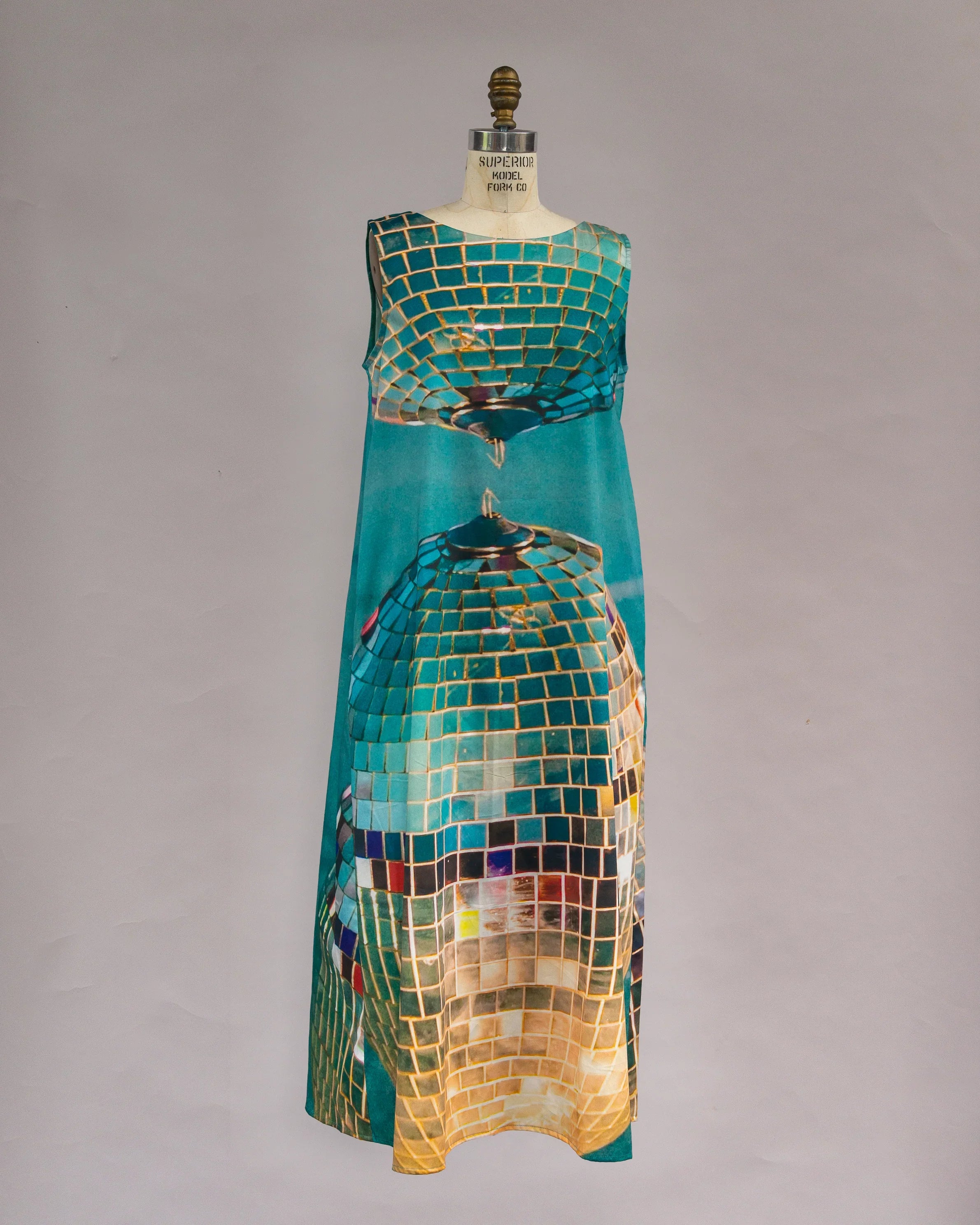 Sleeveless mu'umu'u dress with gold and teal geometric mosaic print on mannequin