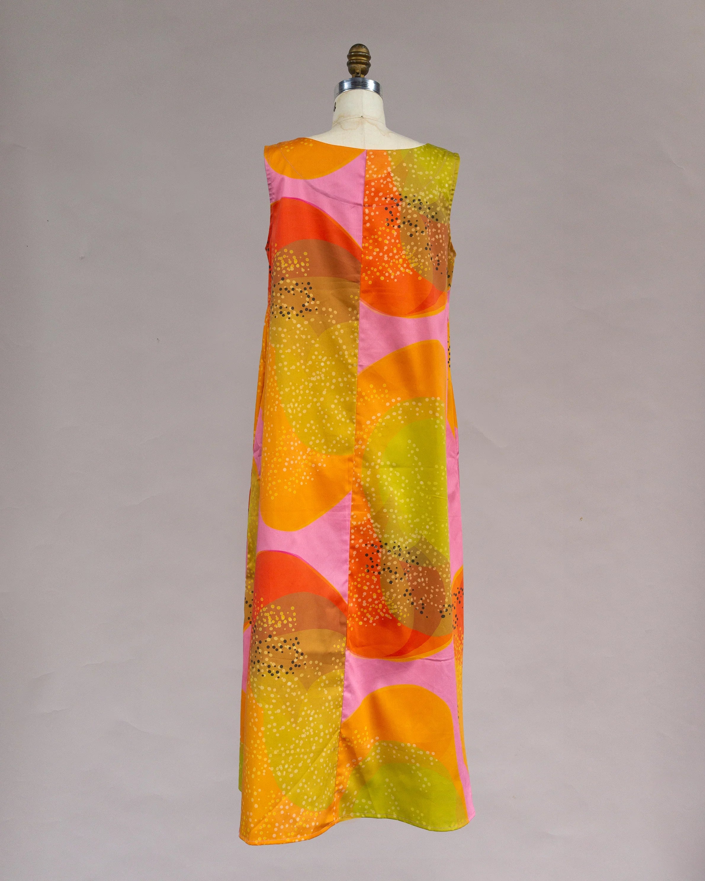 Sleeveless long muumuu dress with abstract orange, pink, and yellow Hawaiian print