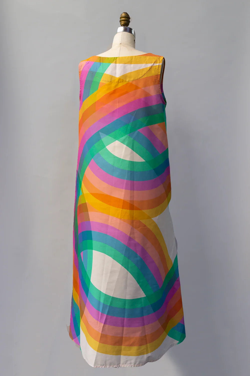 Sleeveless long dress with bold rainbow swirl print on white background, displayed on mannequin