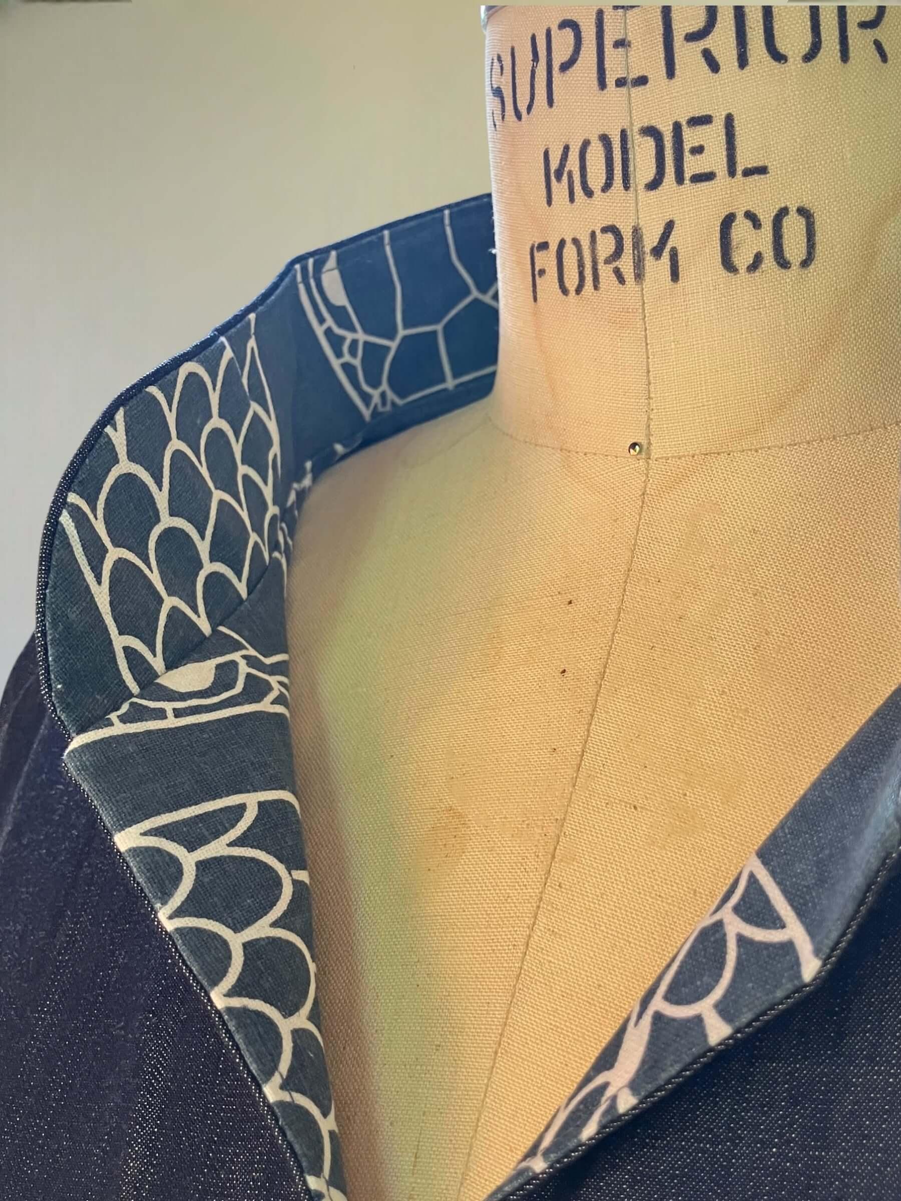 Close-up of a denim dress collar with white Hawaiian-inspired print lining on a dress form