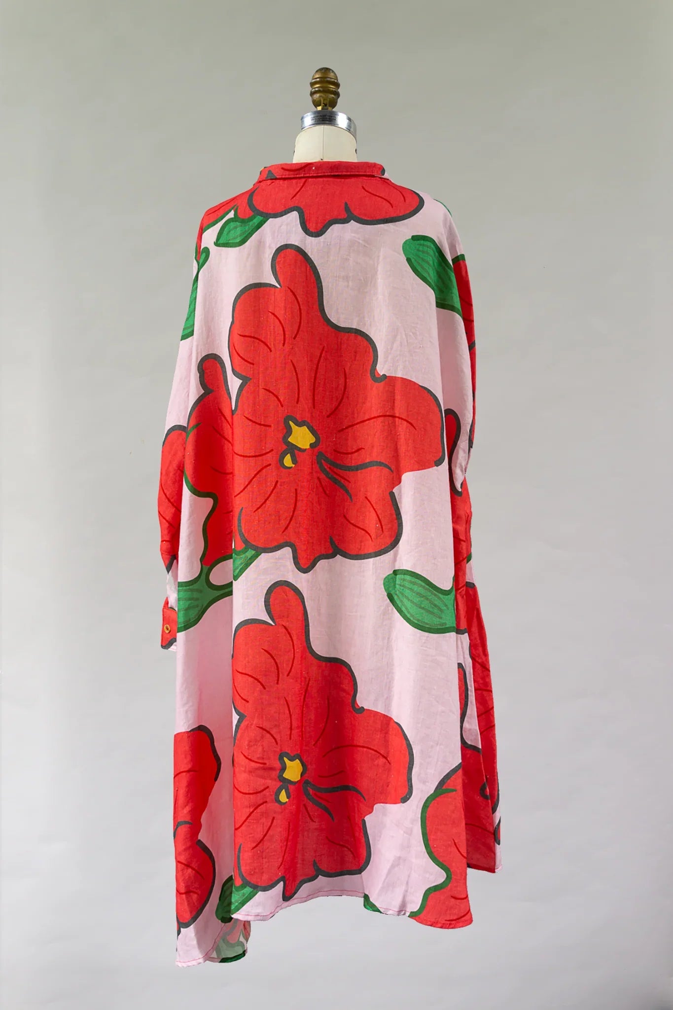 Pink muumuu dress with bold red hibiscus flower print and green leaves, back view