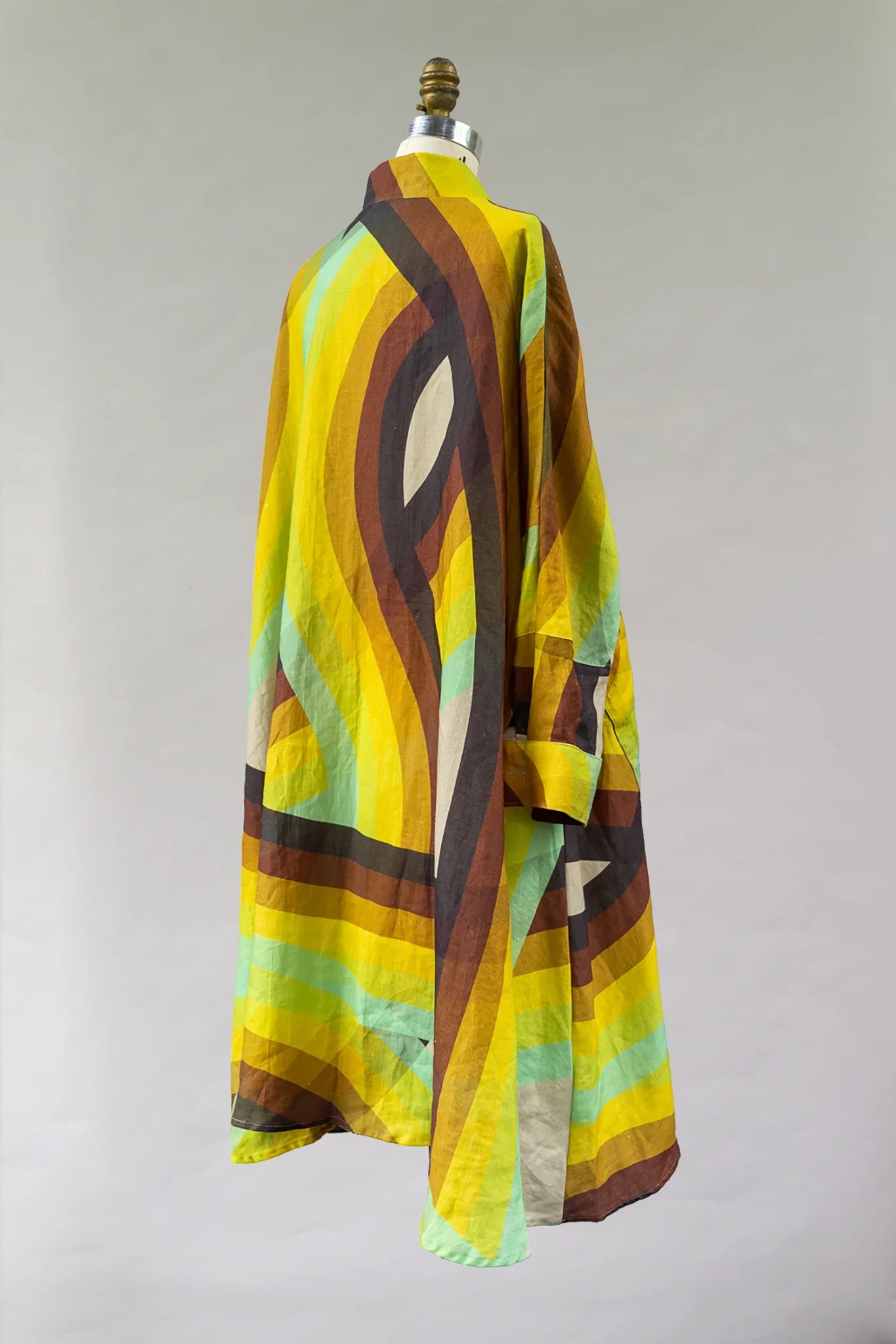 Colorful modern muumuu dress with bold yellow, brown, and green abstract print on mannequin