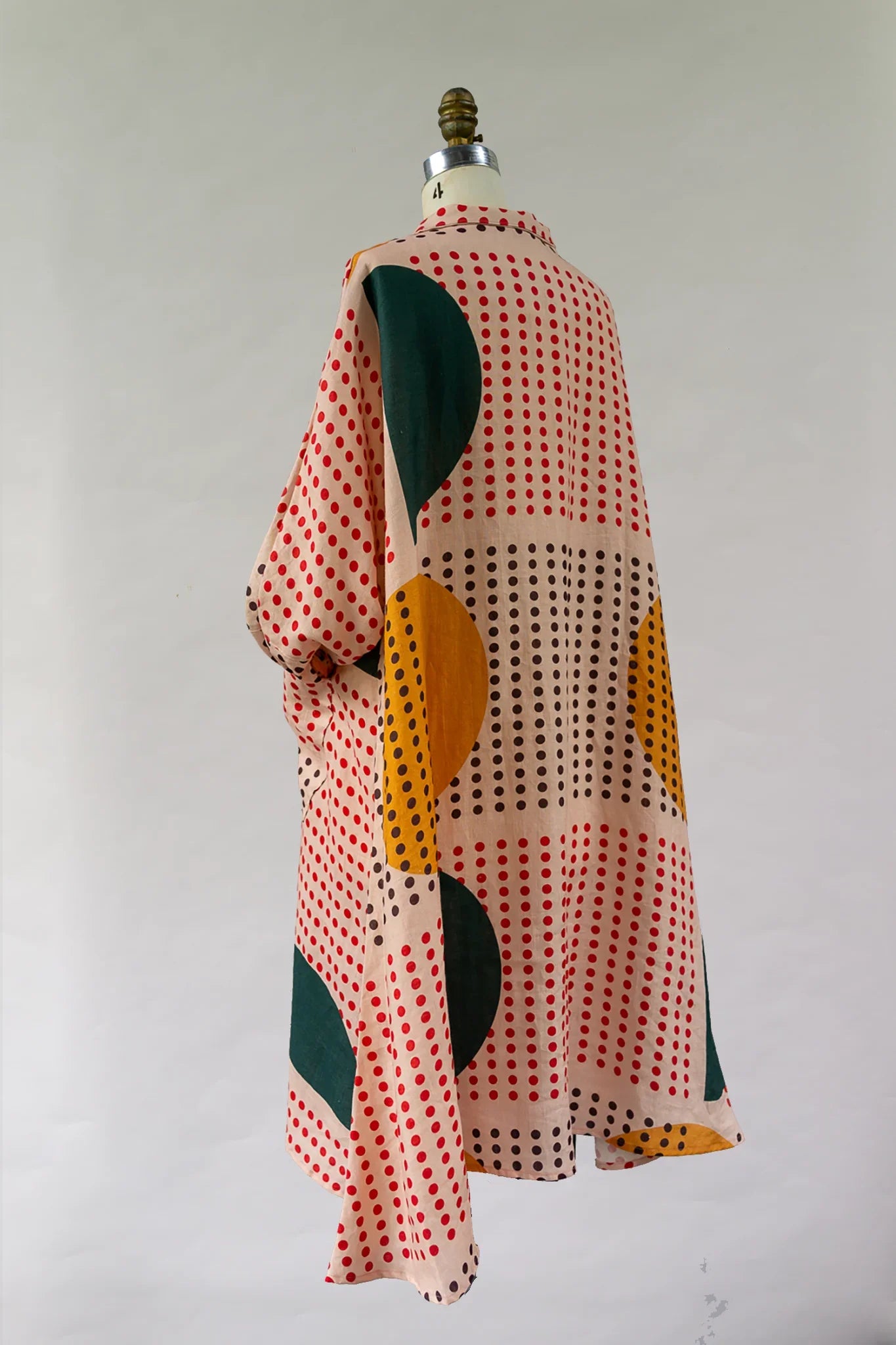Modern muumuu dress with red dot pattern and bold green and yellow circles on fabric