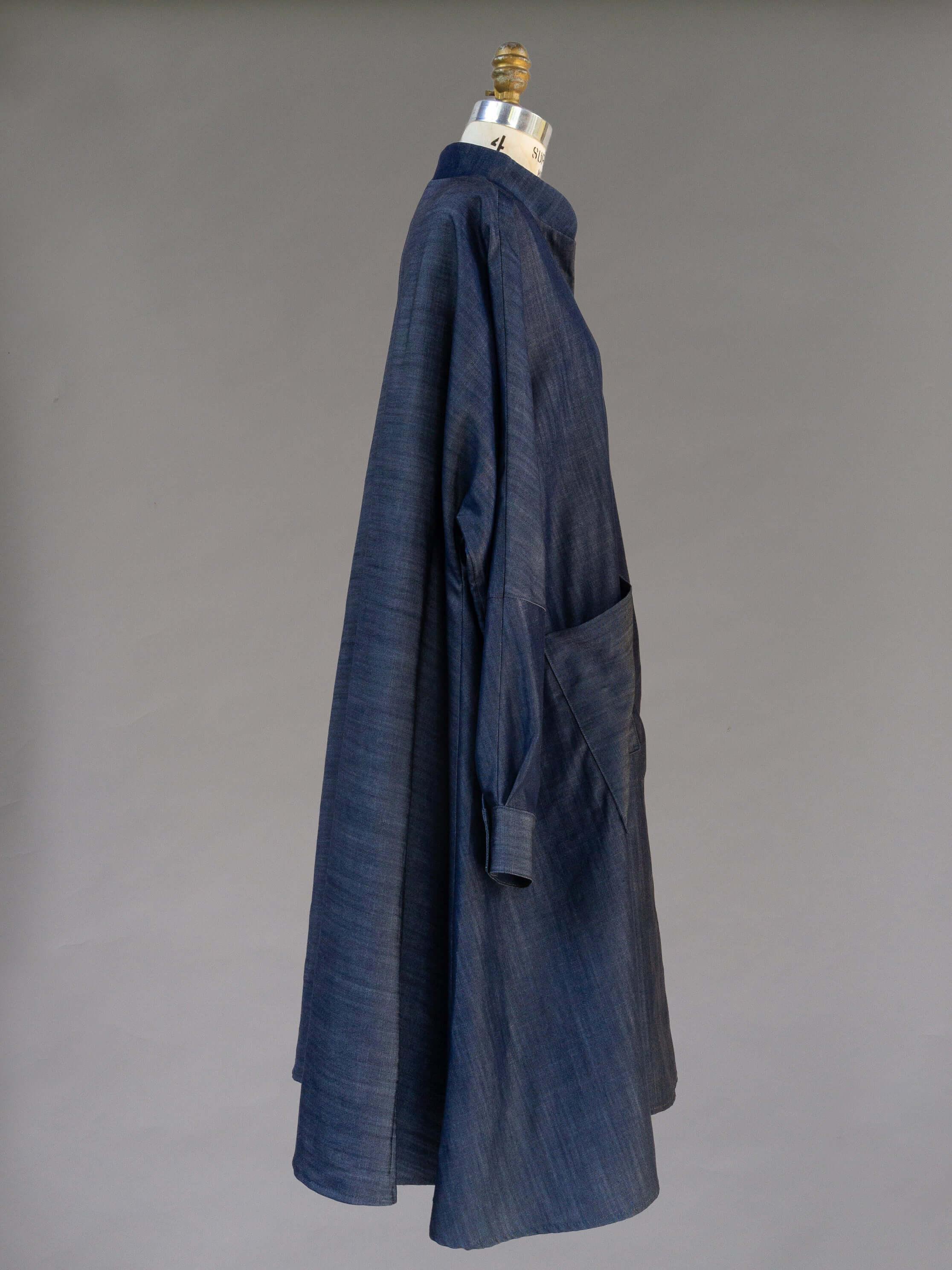 Loose fit indigo denim dress with long sleeves and large front pocket on mannequin