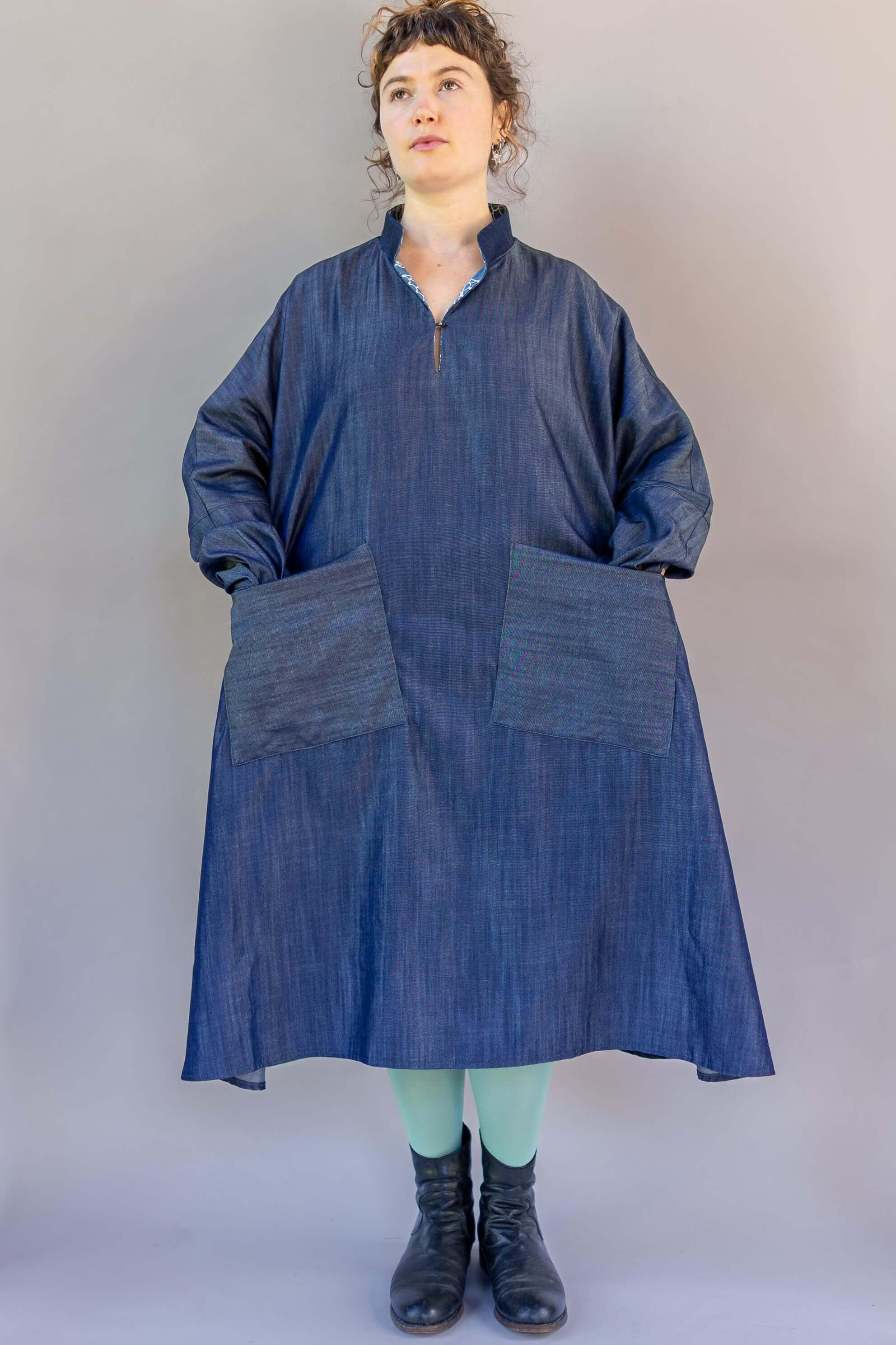 Woman wearing loose-fit denim mu'umu'u dress with long sleeves and front pockets