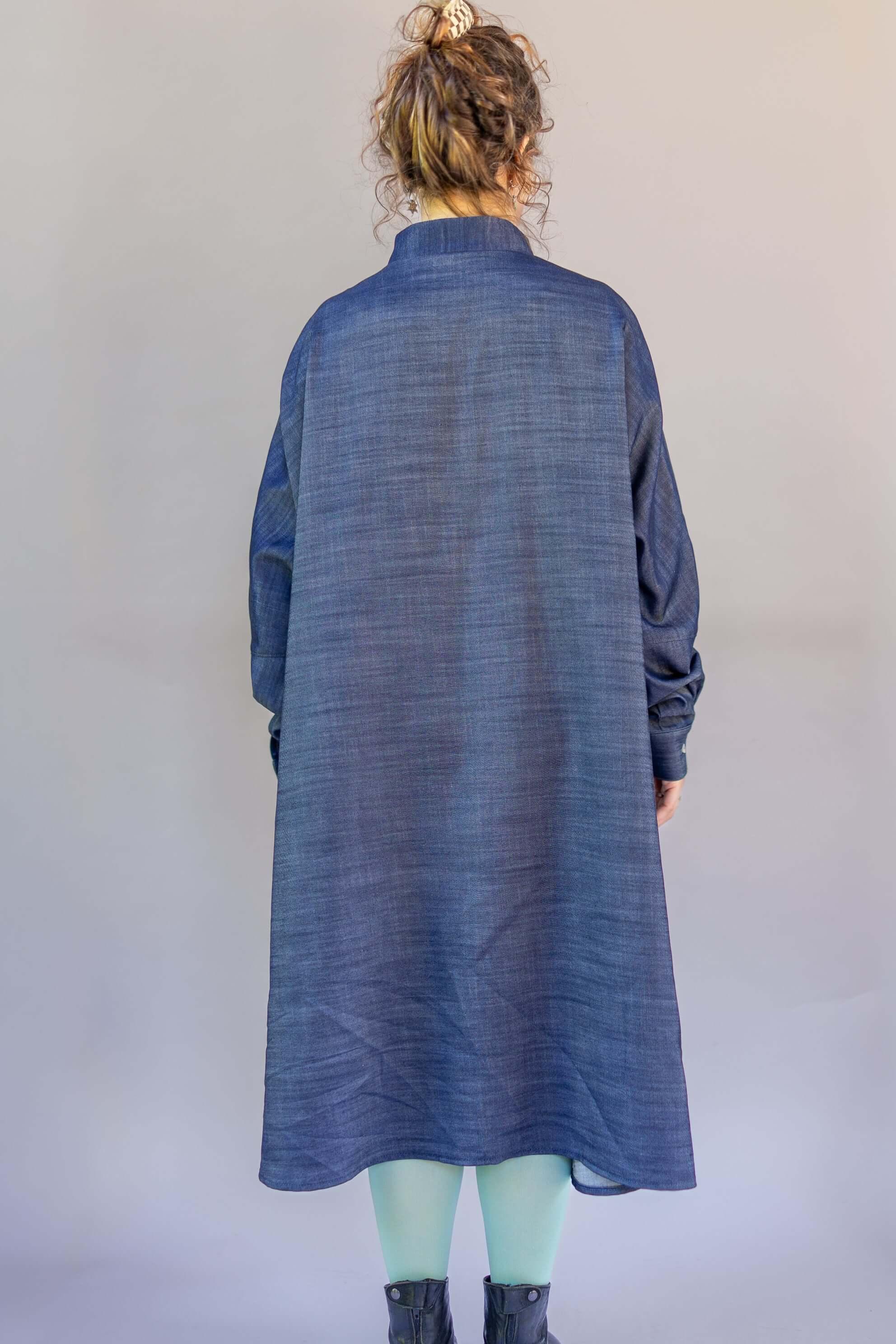 Back view of a woman wearing a long denim mu'umu'u dress with long sleeves.