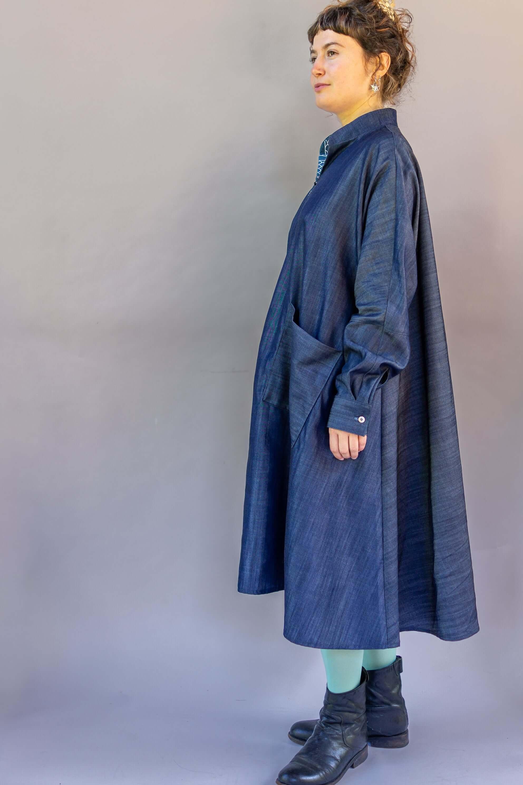 Woman in loose-fitting denim mu'umu'u dress with large pocket, green tights, black boots