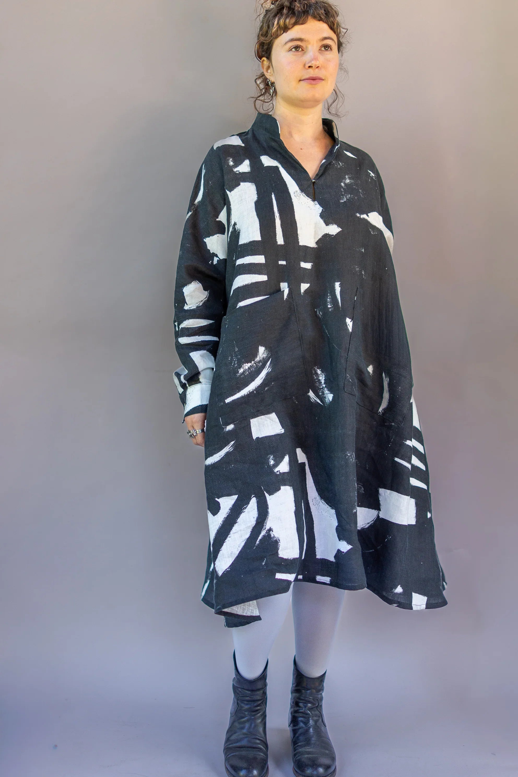 Woman wearing a modern black and white abstract print muumuu dress with boots