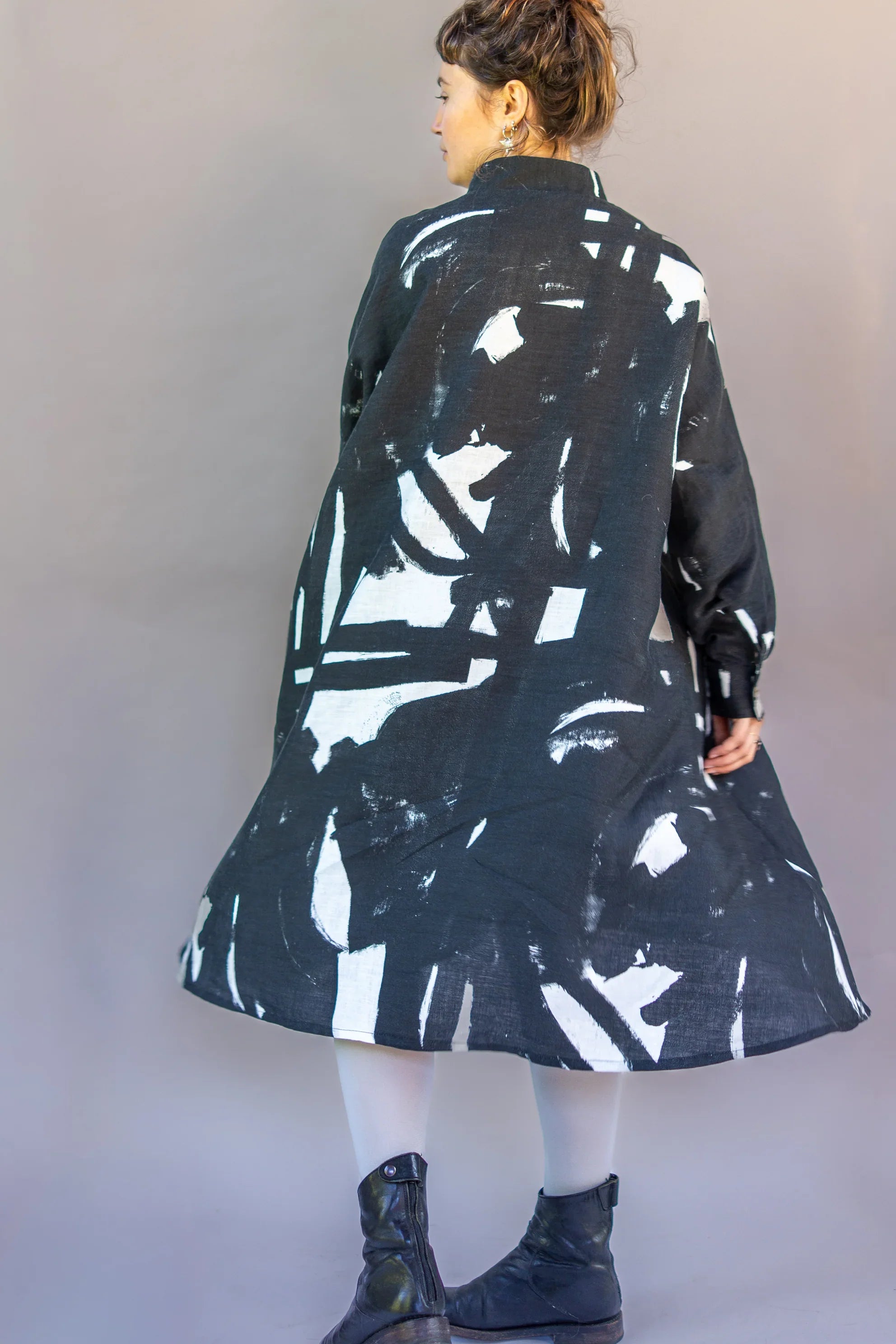Woman wearing a modern black and white abstract print muumuu dress with boots