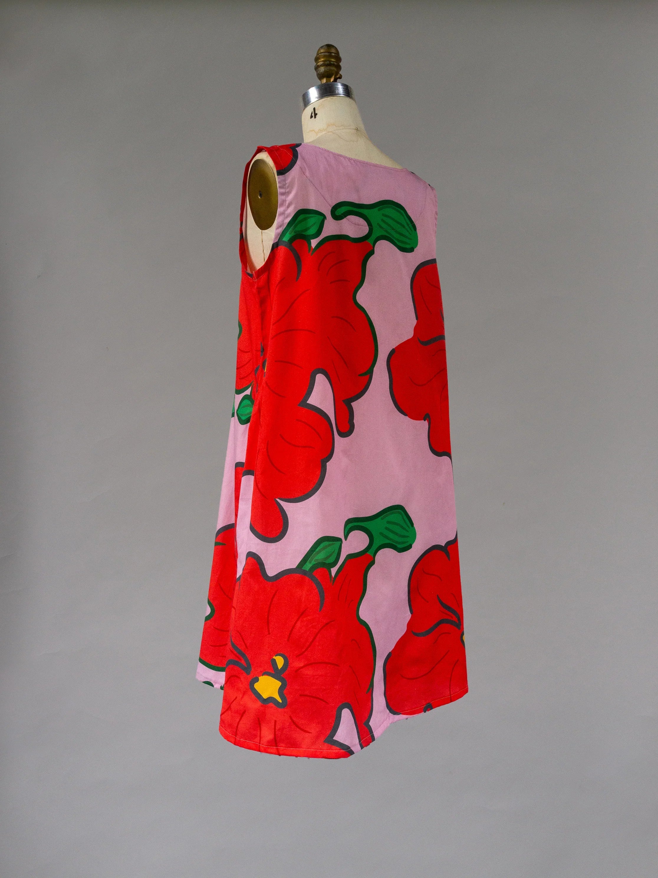 Sleeveless pink mu'umu'u dress with bold red floral Hawaiian print on mannequin
