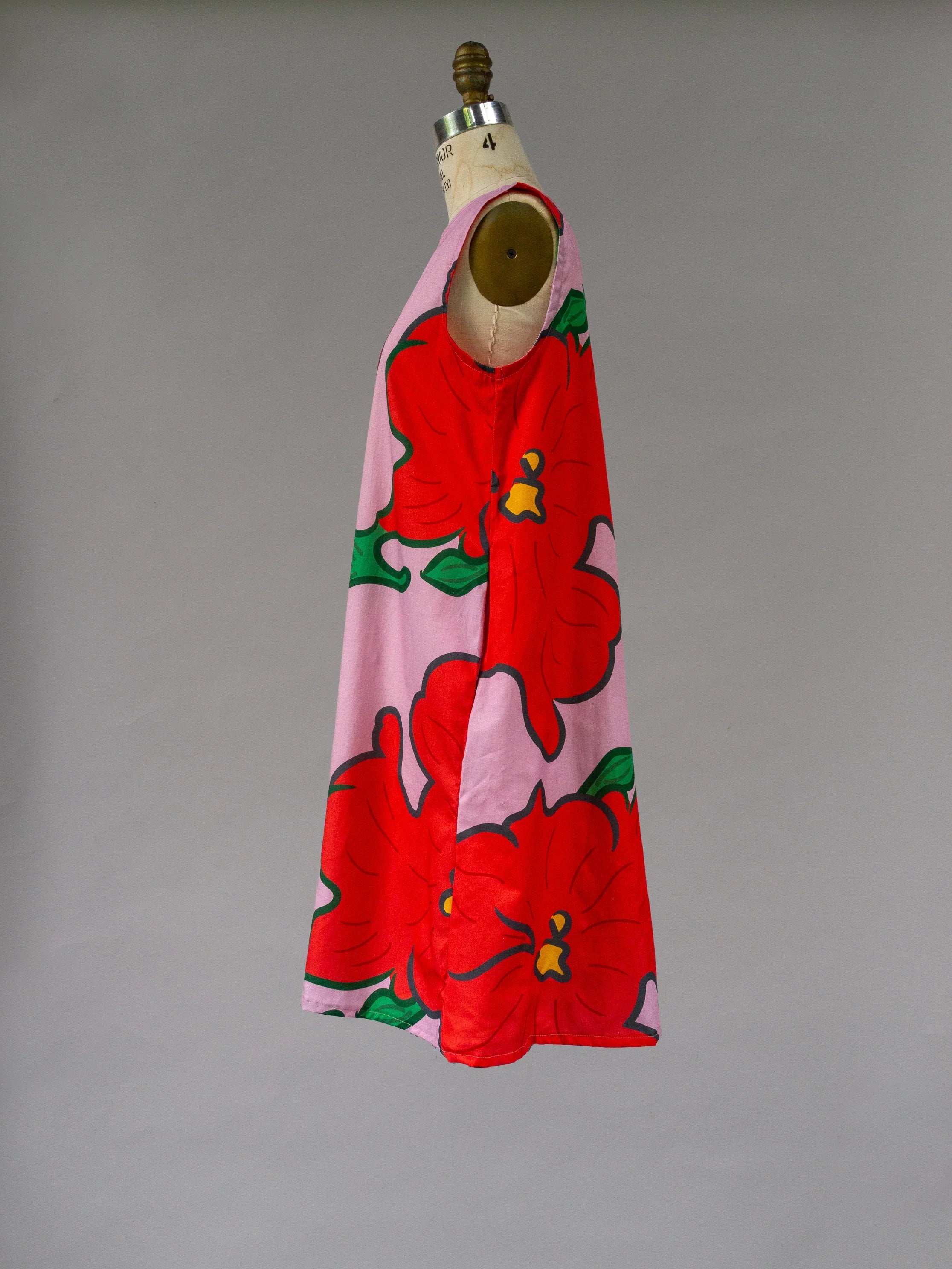 Pink modern muumuu dress with large red Hawaiian hibiscus floral print on mannequin