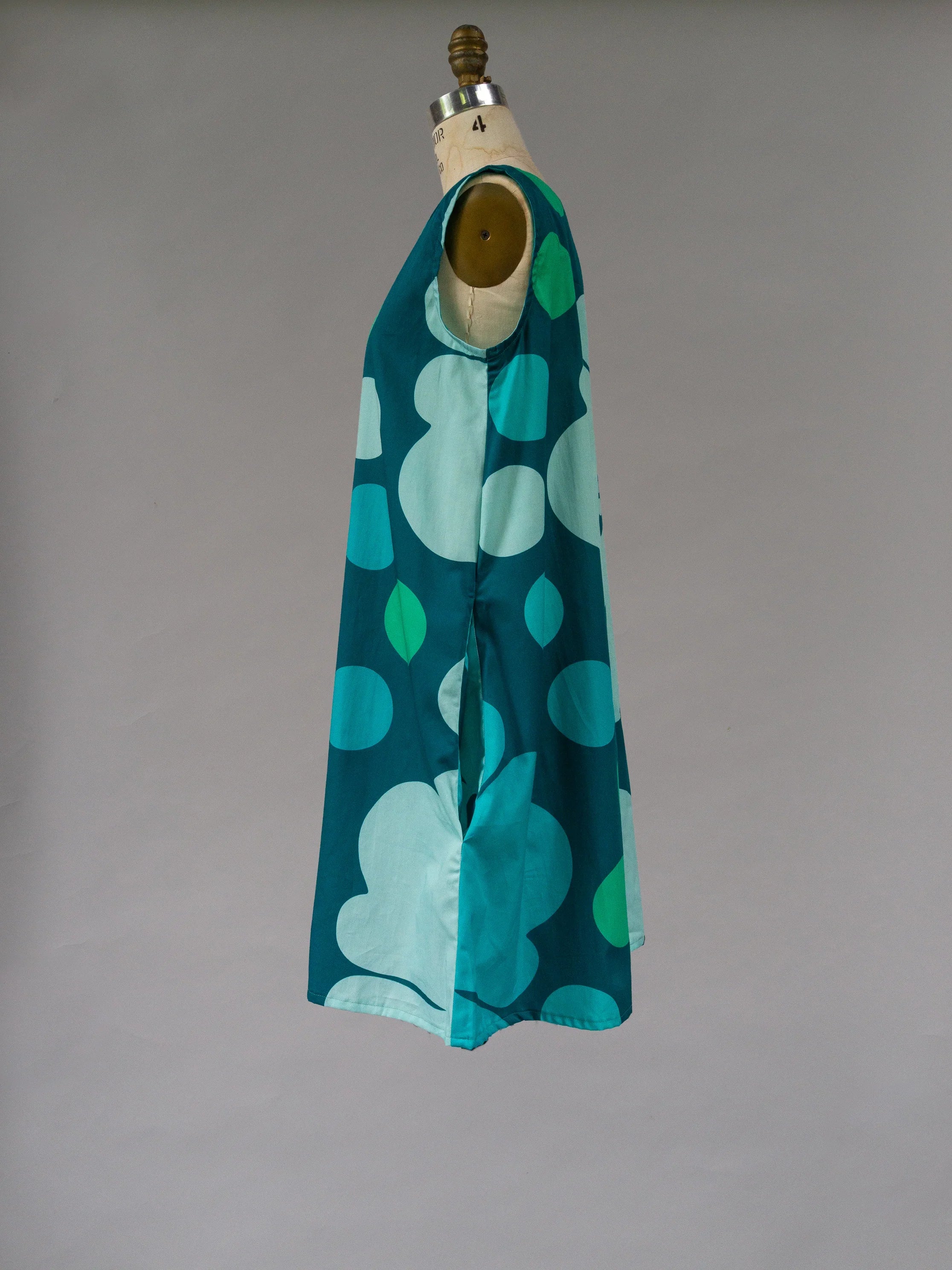 Sleeveless blue and teal Hawaiian print dress with abstract shapes on a mannequin