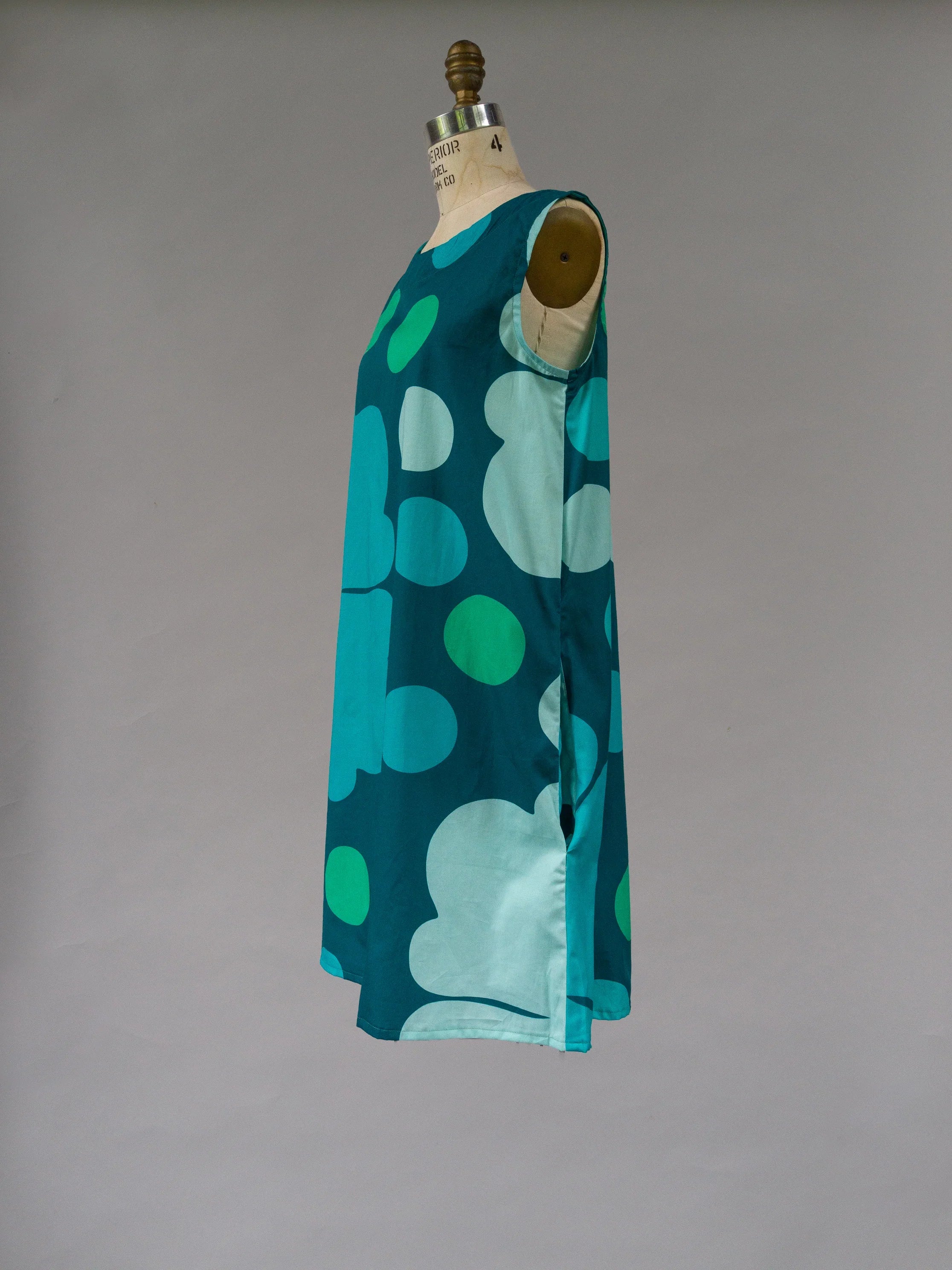 Sleeveless teal muumuu dress with bold abstract Hawaiian print on mannequin