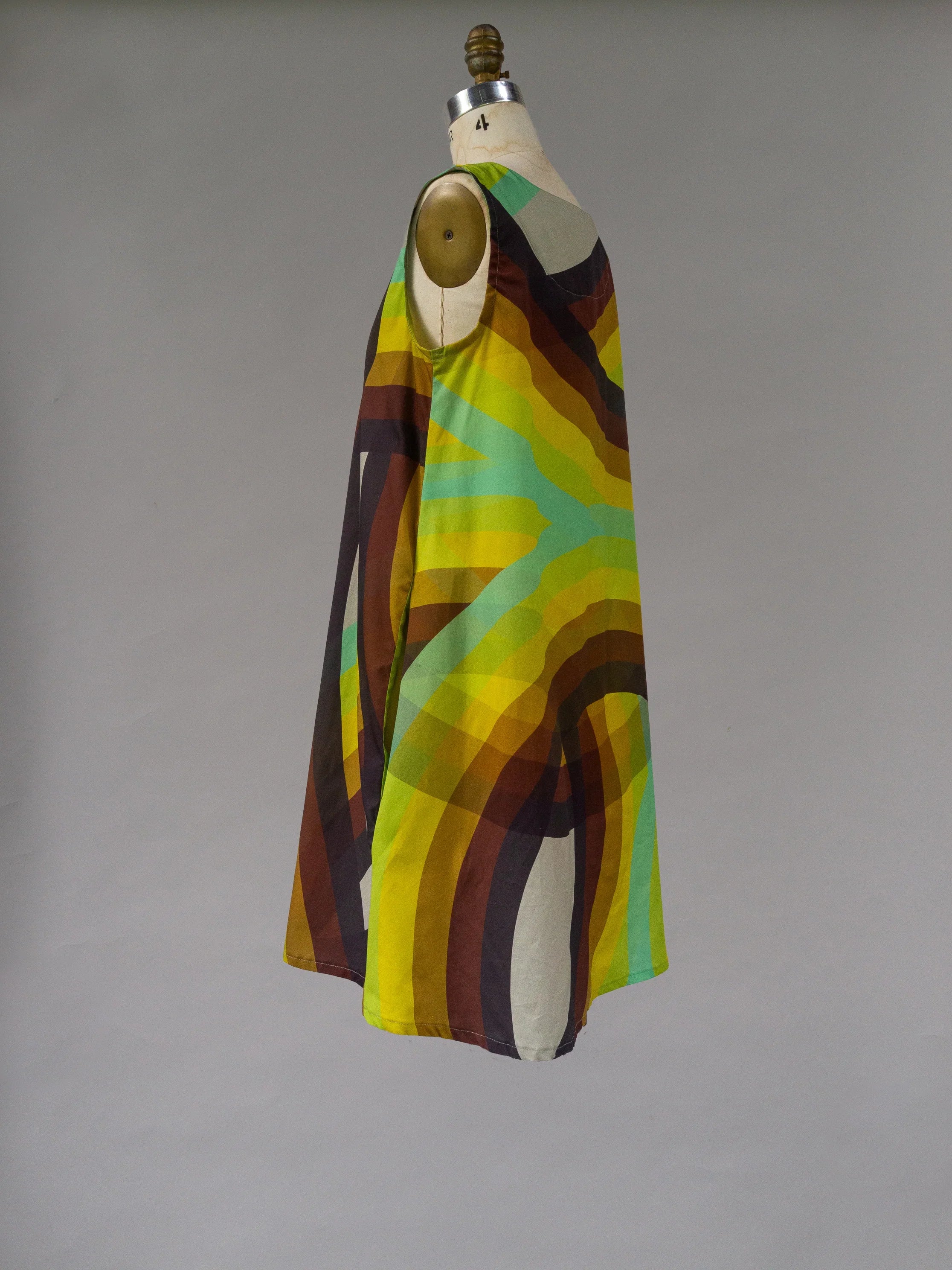 Sleeveless muumuu dress with bold yellow, green, and brown abstract rainbow print on mannequin